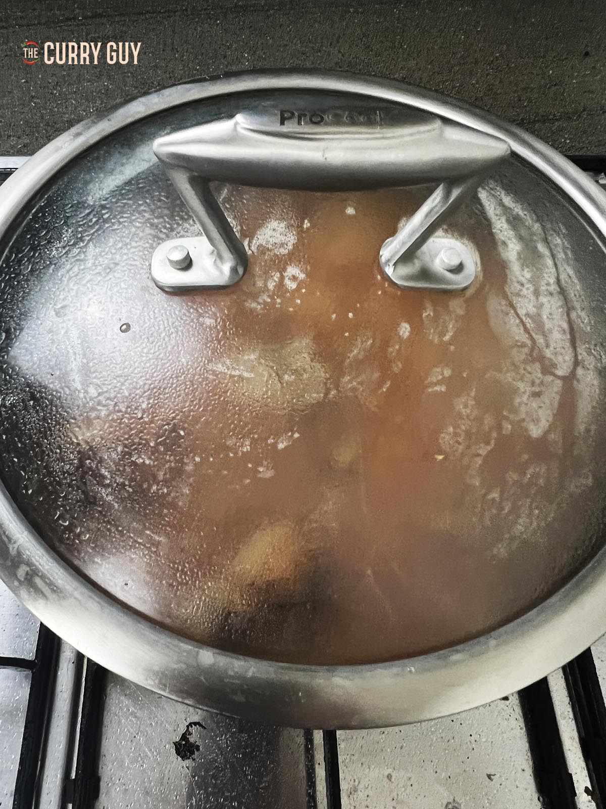Covering the pan to simmer the curry.
