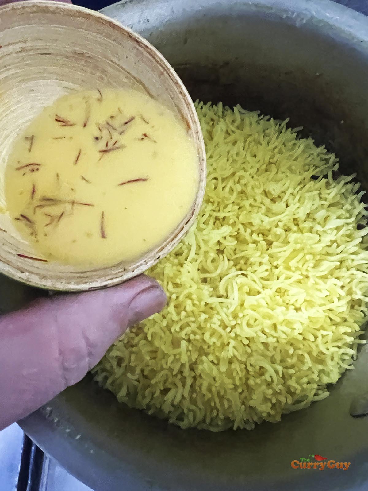 Pouring saffron milk into the rice.