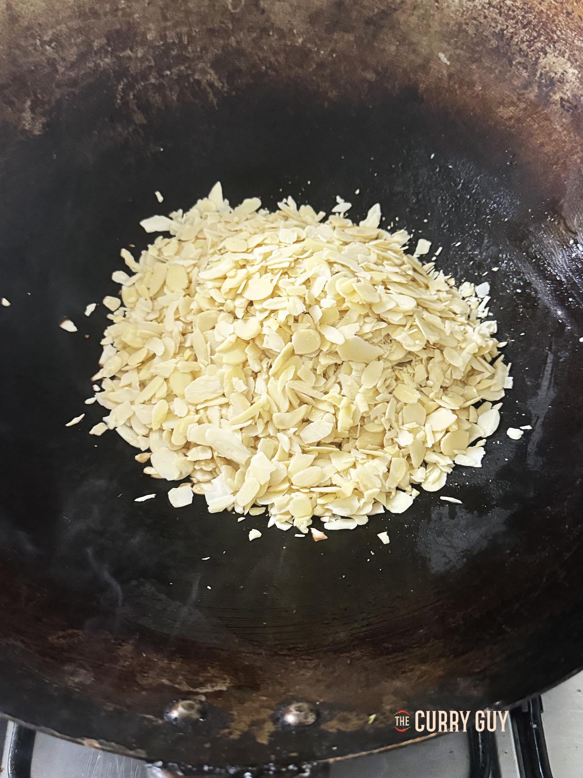 Toasting the flaked almonds in a wok.