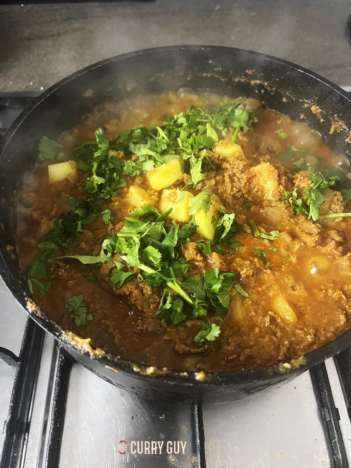 Adding chopped coriander to the curry to simmer and flavour the sauce.