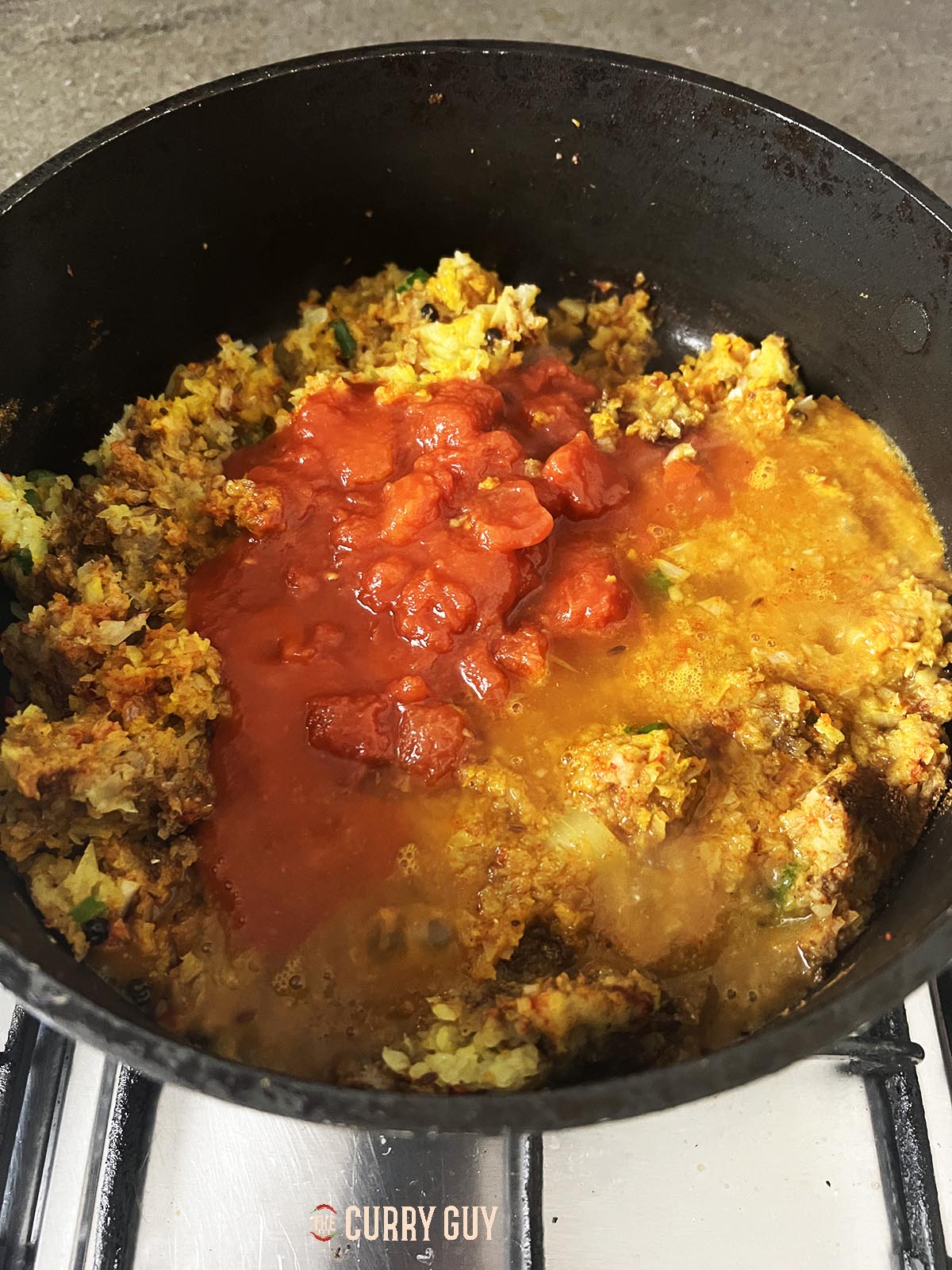 Adding the chopped tomatoes and water to the pan.