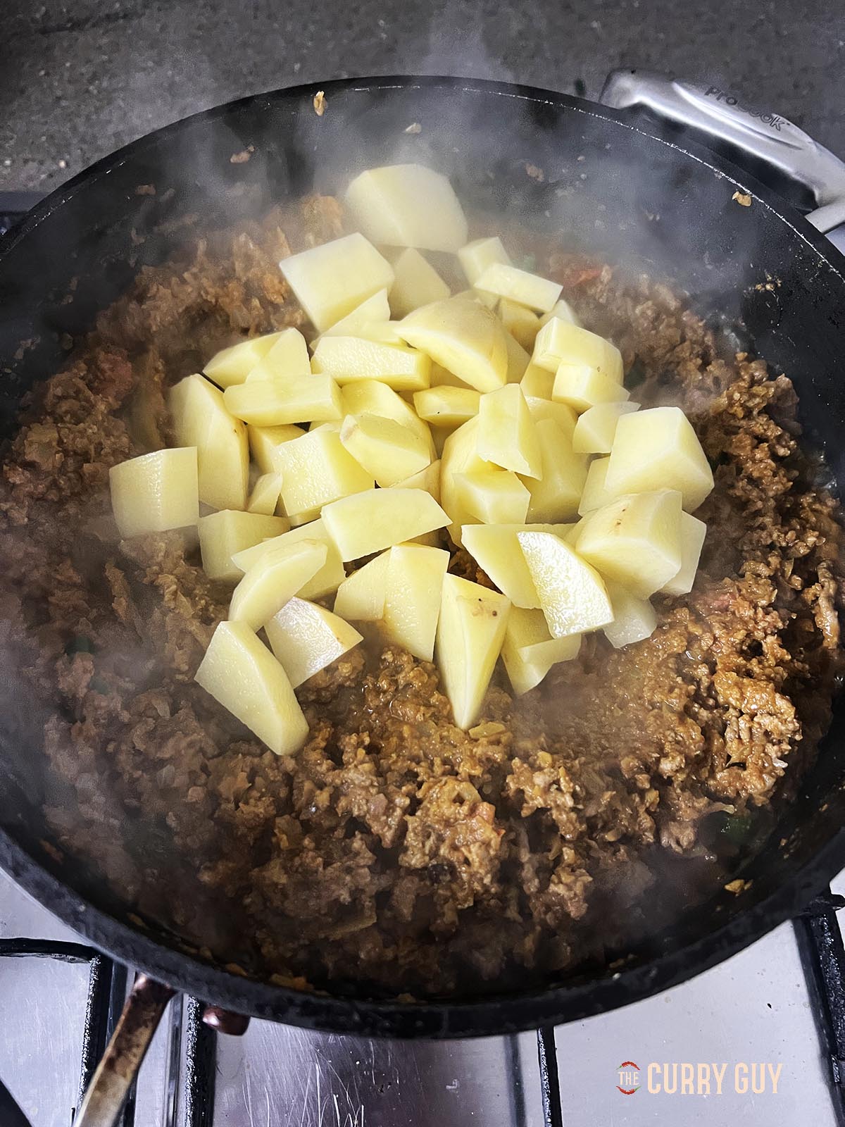 Adding the cubed potatoes to the pan.