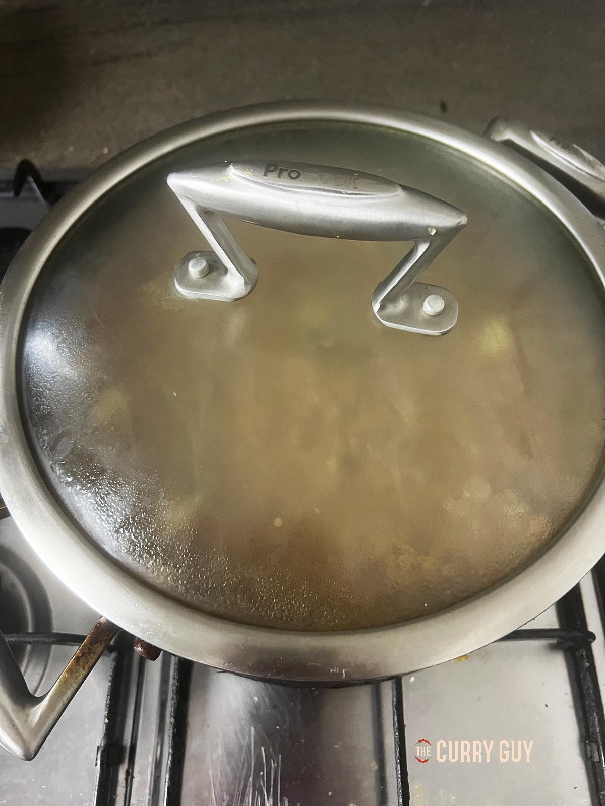 Simmering the curry with the lid on the pan.