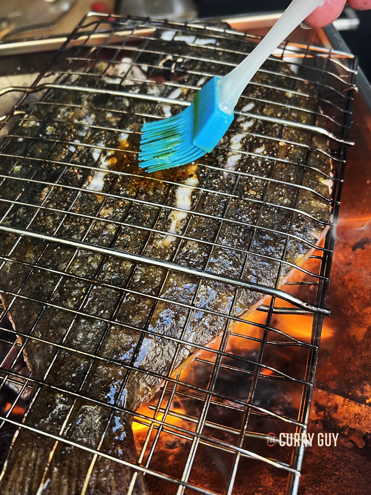 Turing the fish over and basting it.