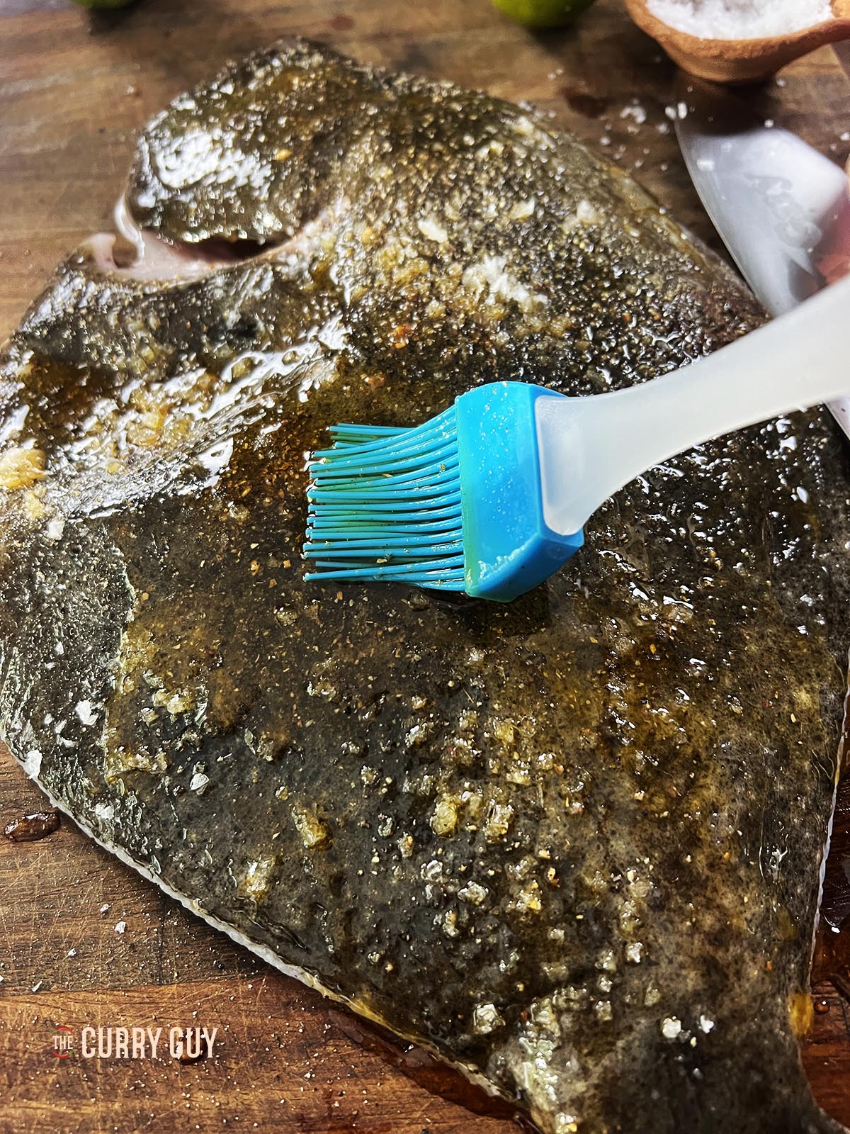 Basting the turbot before placing it in the fish basket to cook over fire.