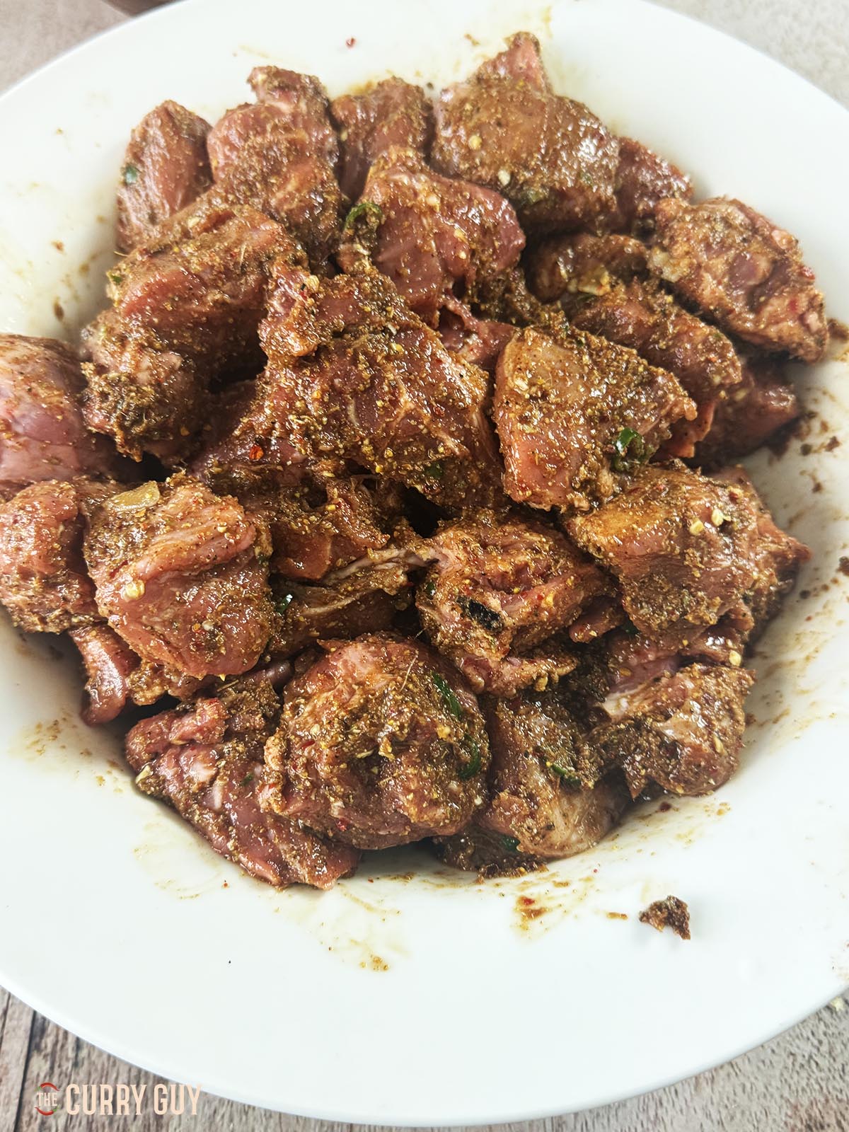 The pork marinating in the spice paste in a bowl.