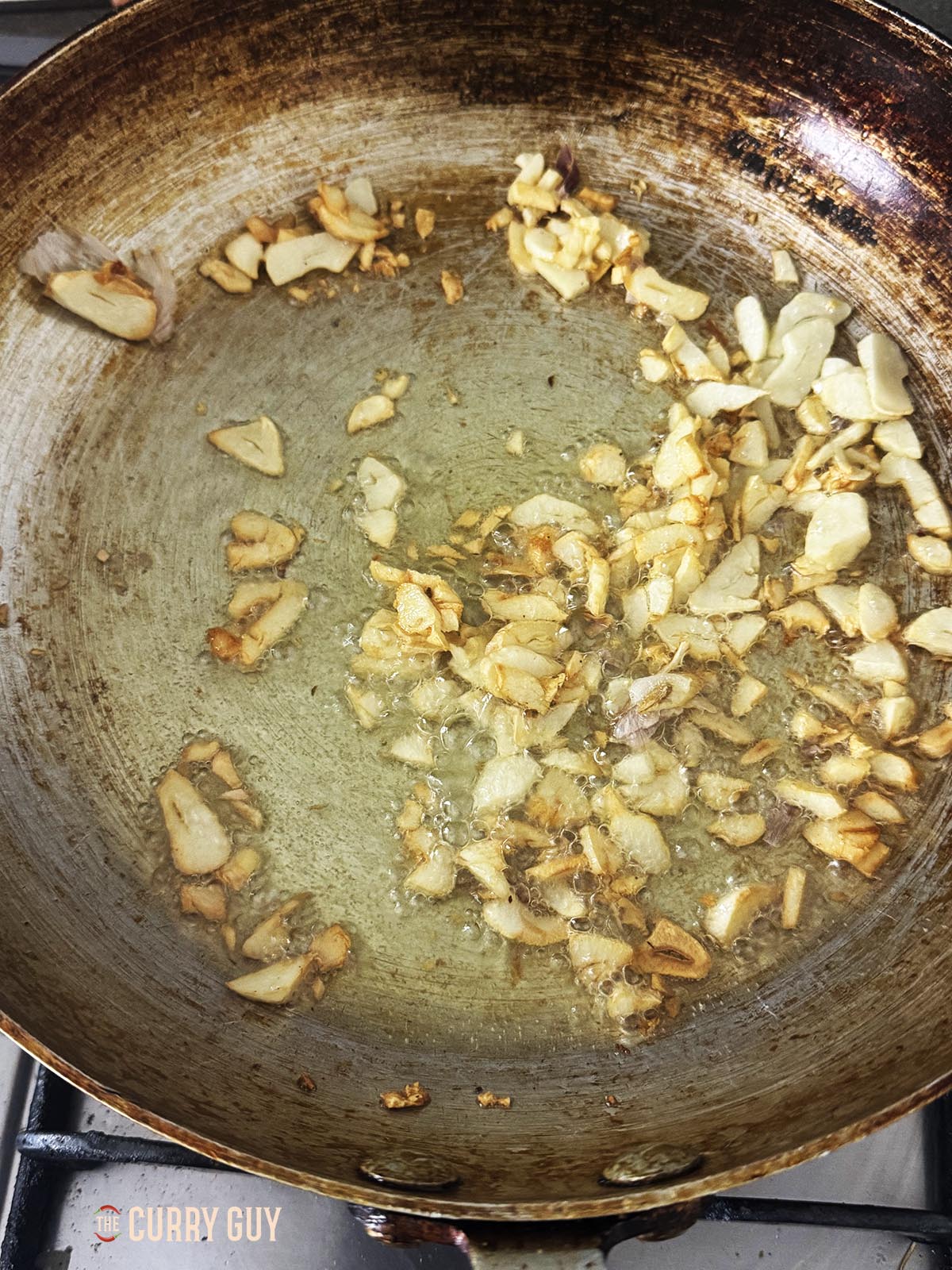 Frying garlic slivers in oil to brown them.