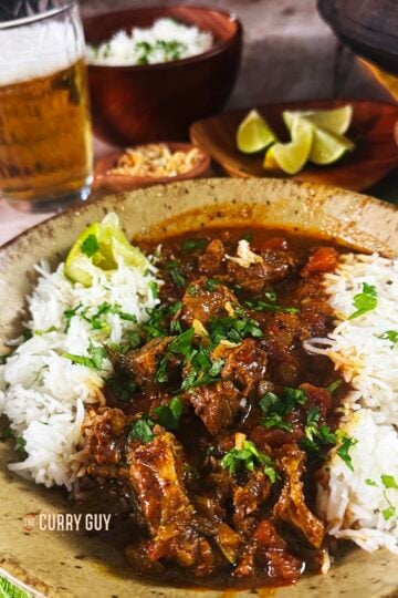 Pork vindaloo served with rice and garnished with fried garlic and chopped coriander.
