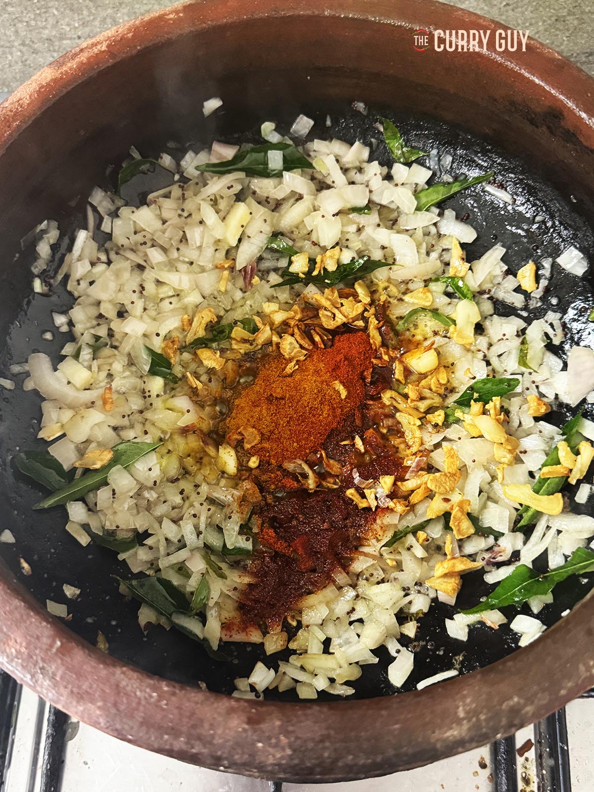 Stirring the chilli powder and ground turmeric into the onions as they fry.