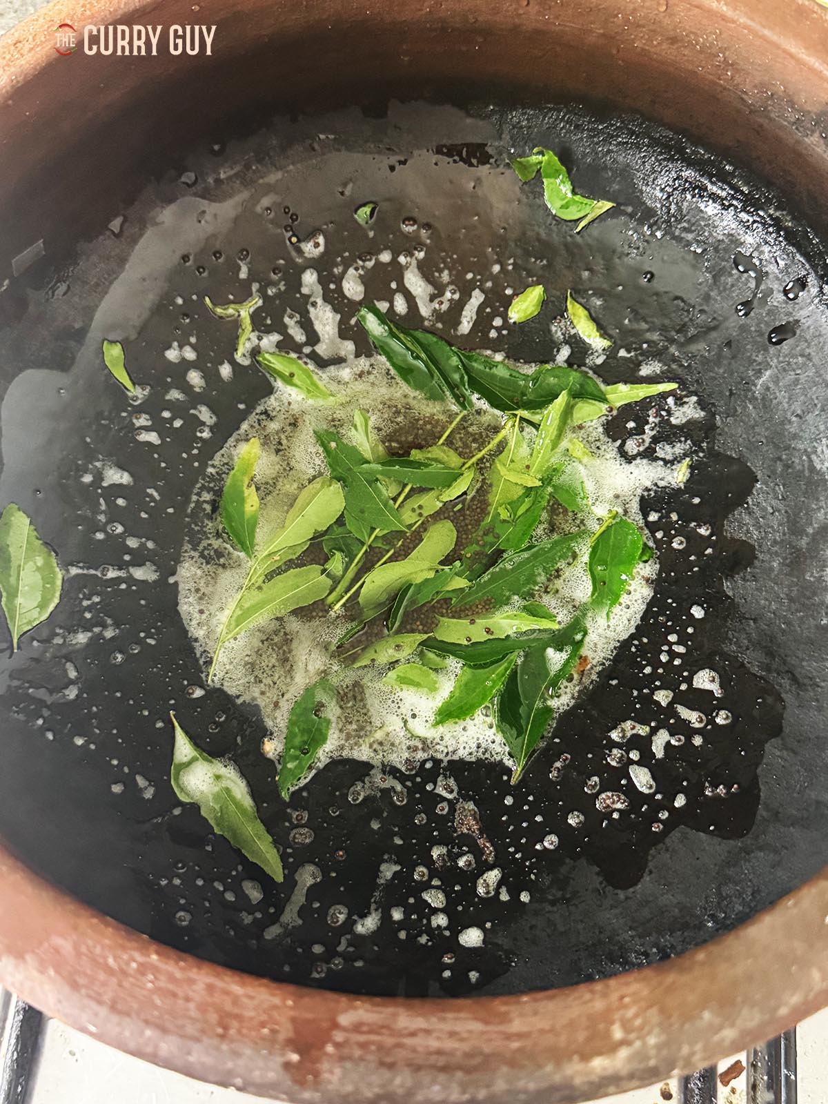Frying mustard seeds and curry leaves in coconut oil over a medium-hight heat.