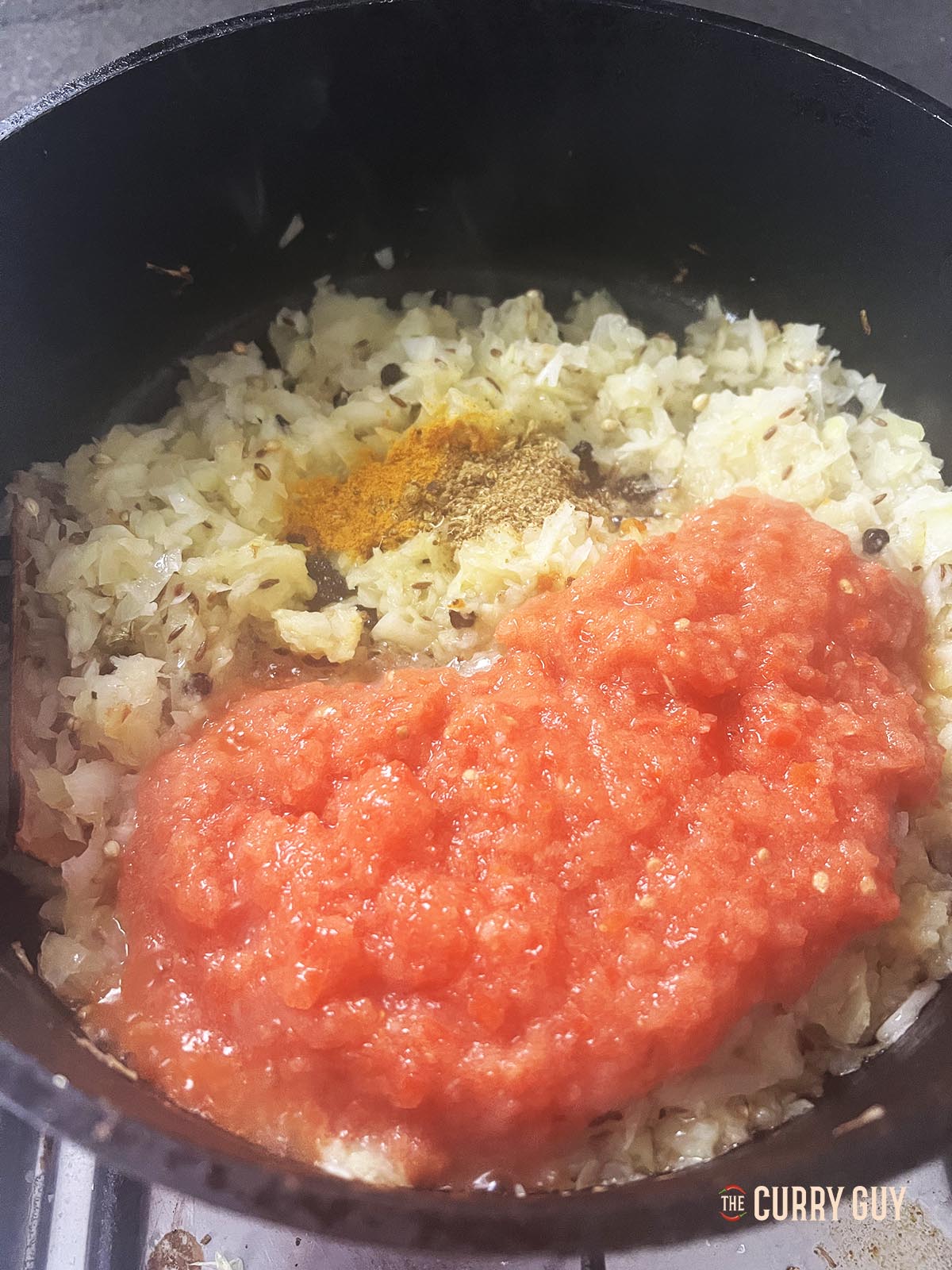 Adding turmeric and chopped tomatoes to the pan.