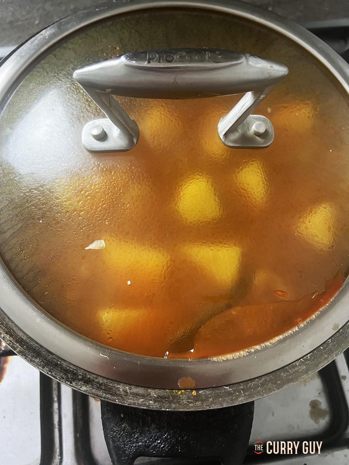 Covering the pan to let the potatoes simmer and cook through.