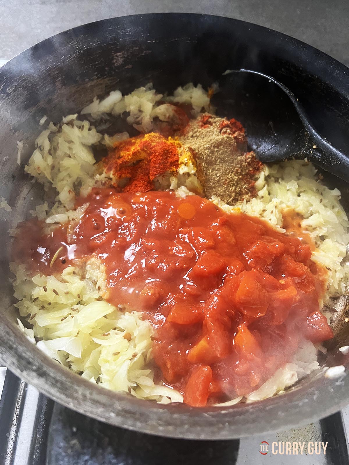Adding the ground spices and chopped tomatoes to the pan.