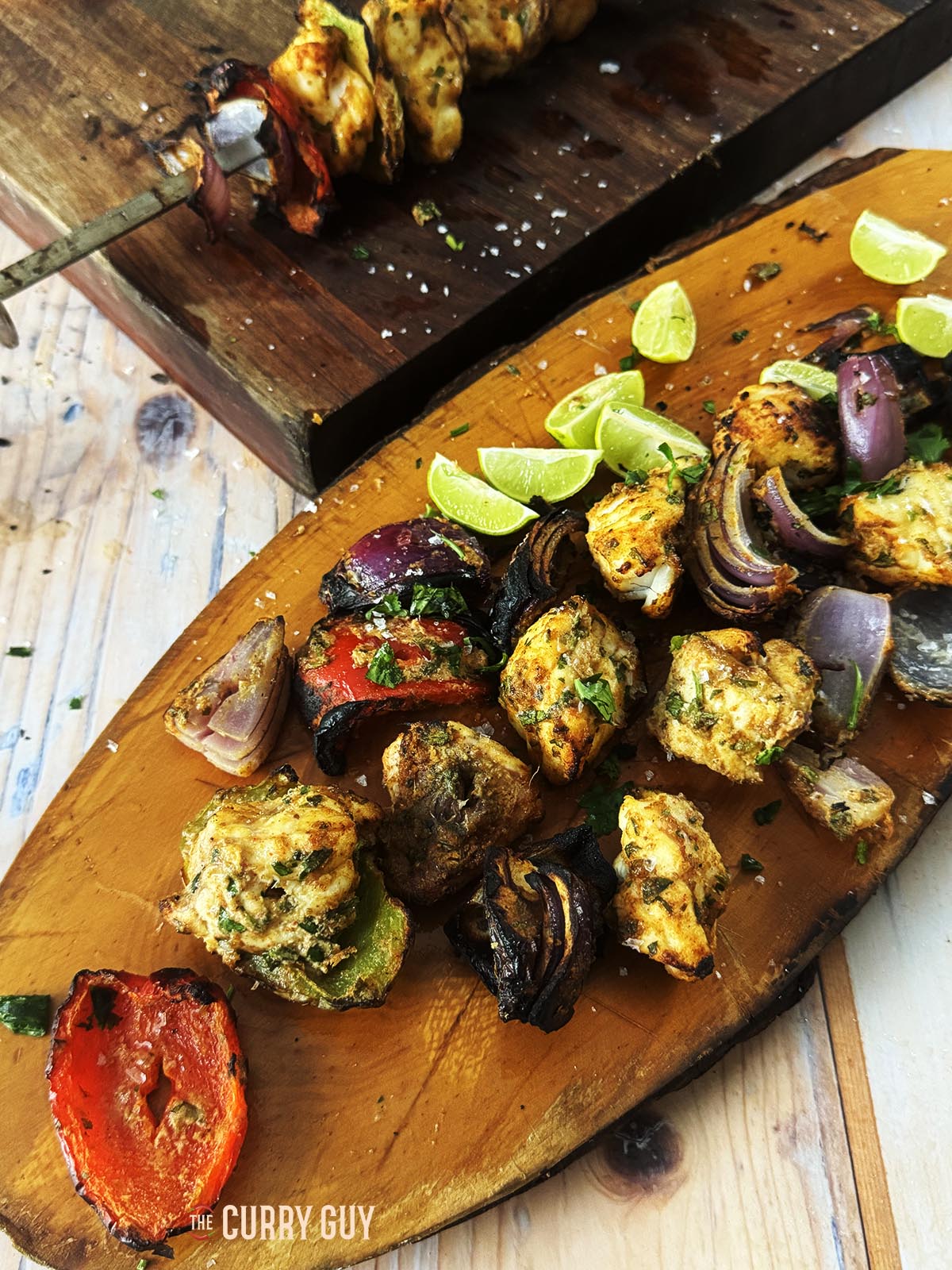 Grilled monkfish and vegetables on a serving platter with lime wedges. 