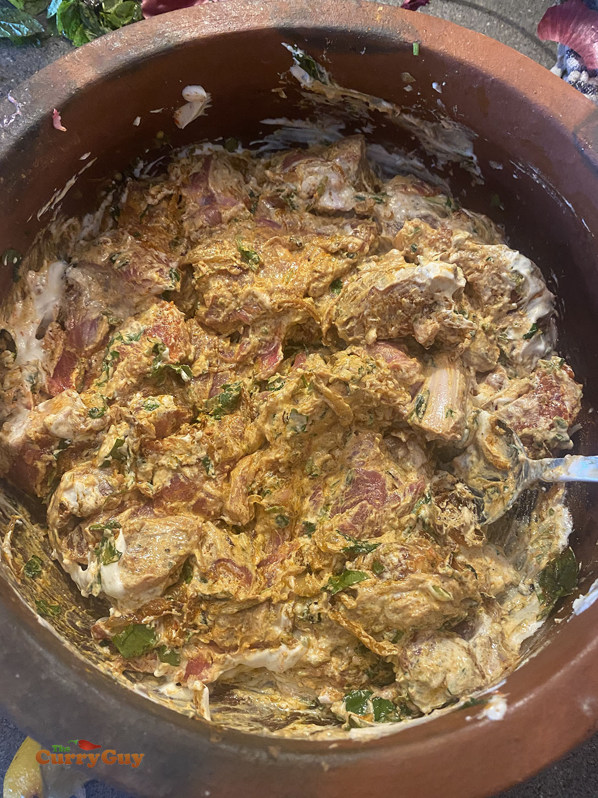 Adding yoghurt to the pot to finish off the marinade.