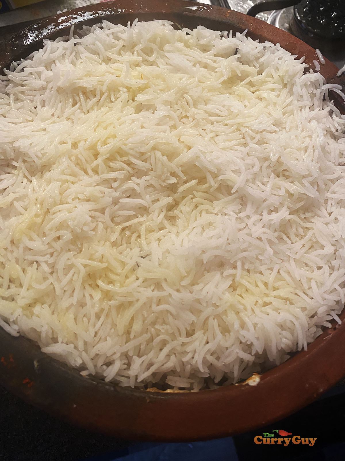Topping the biryani with the second batch of par-cooked rice.