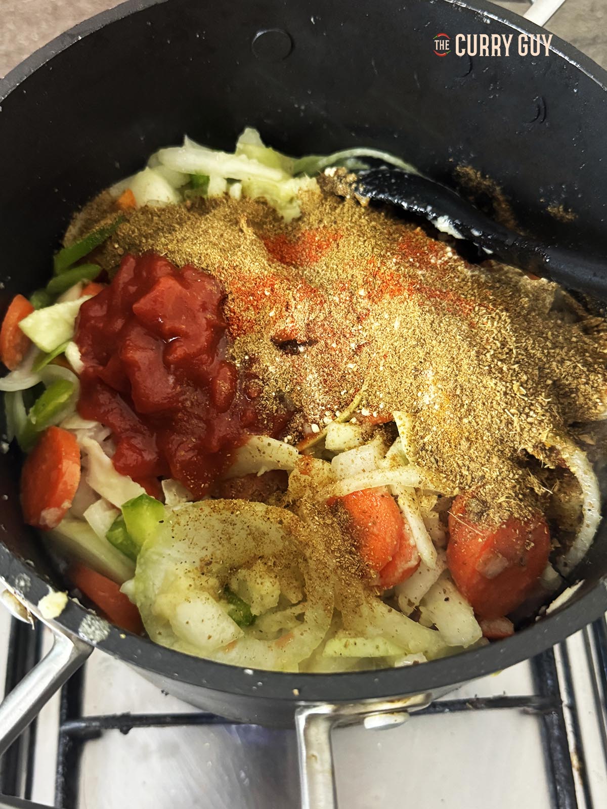 Adding the paprika, ground coriander, cumin, garam masala, fenugreek and turmeric to the pot.