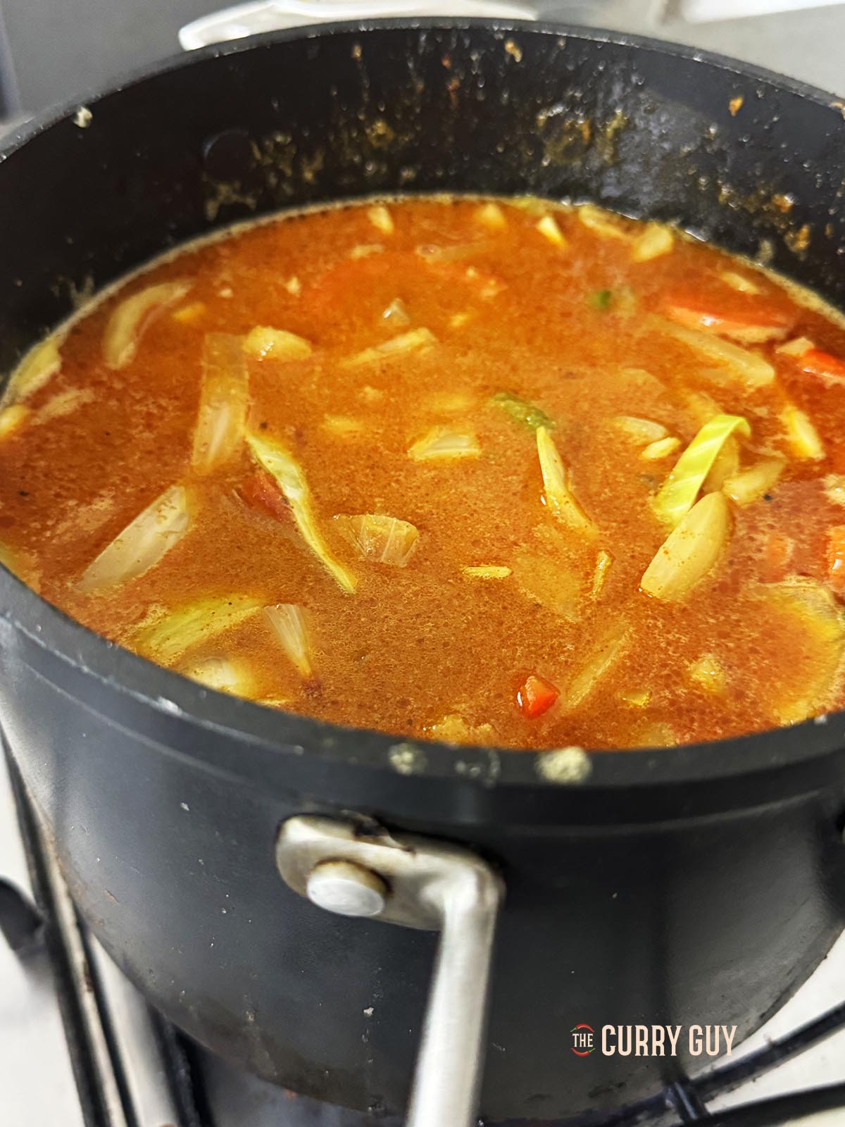 Bringing the base sauce to a simmer in an open pot.