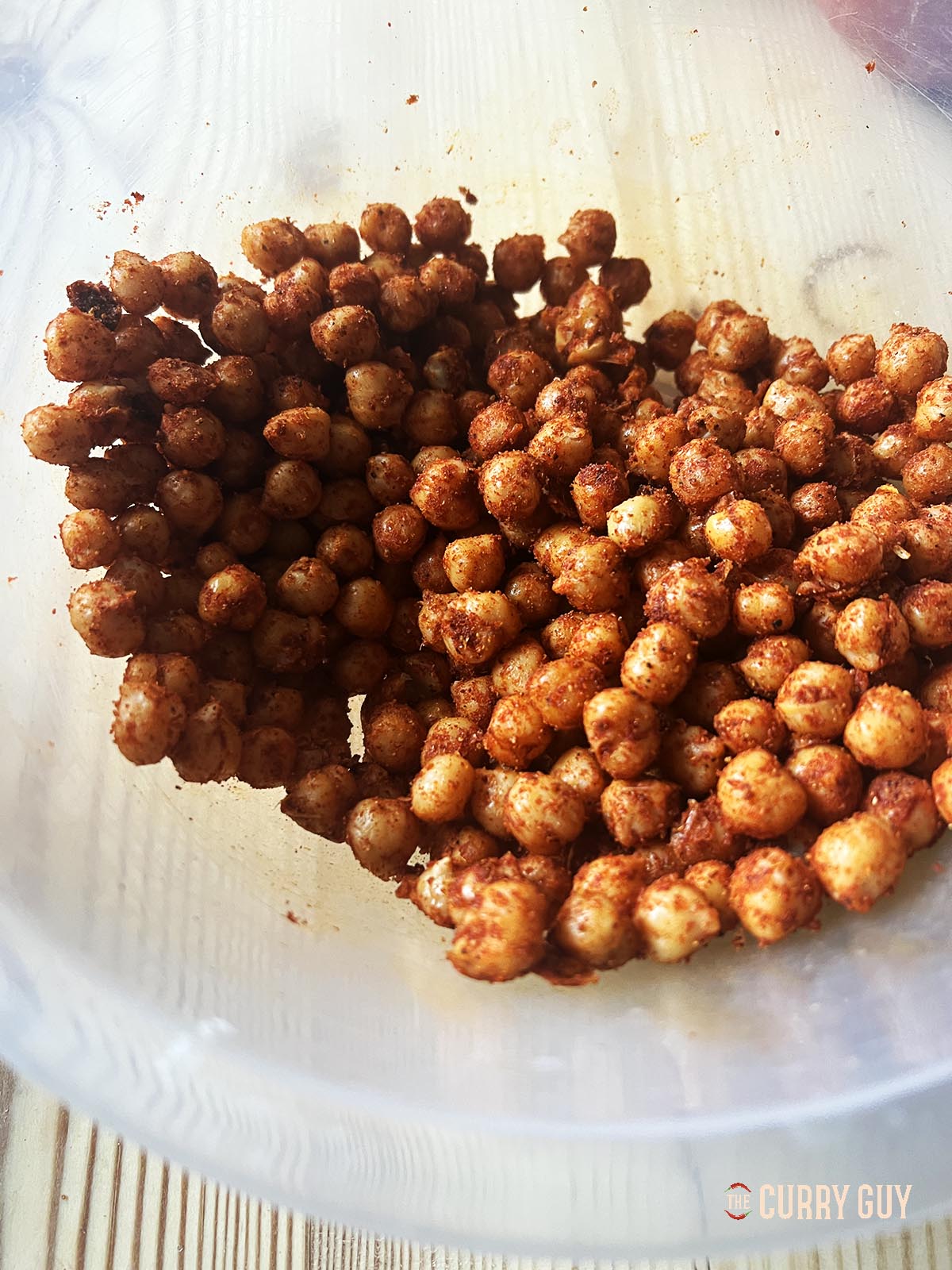 Mixing the chickpeas with the olive oil and ground spices in a mixing bowl.