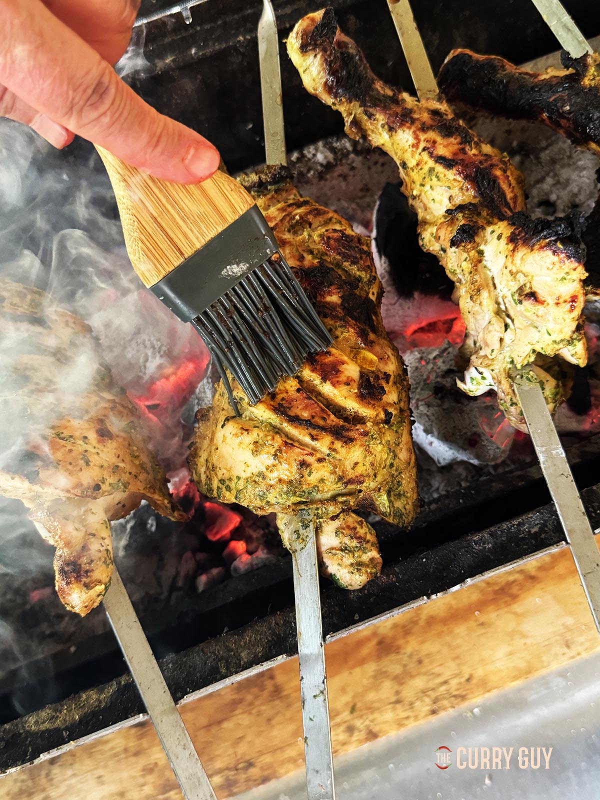 Basting the grilled chicken legs with melted ghee.