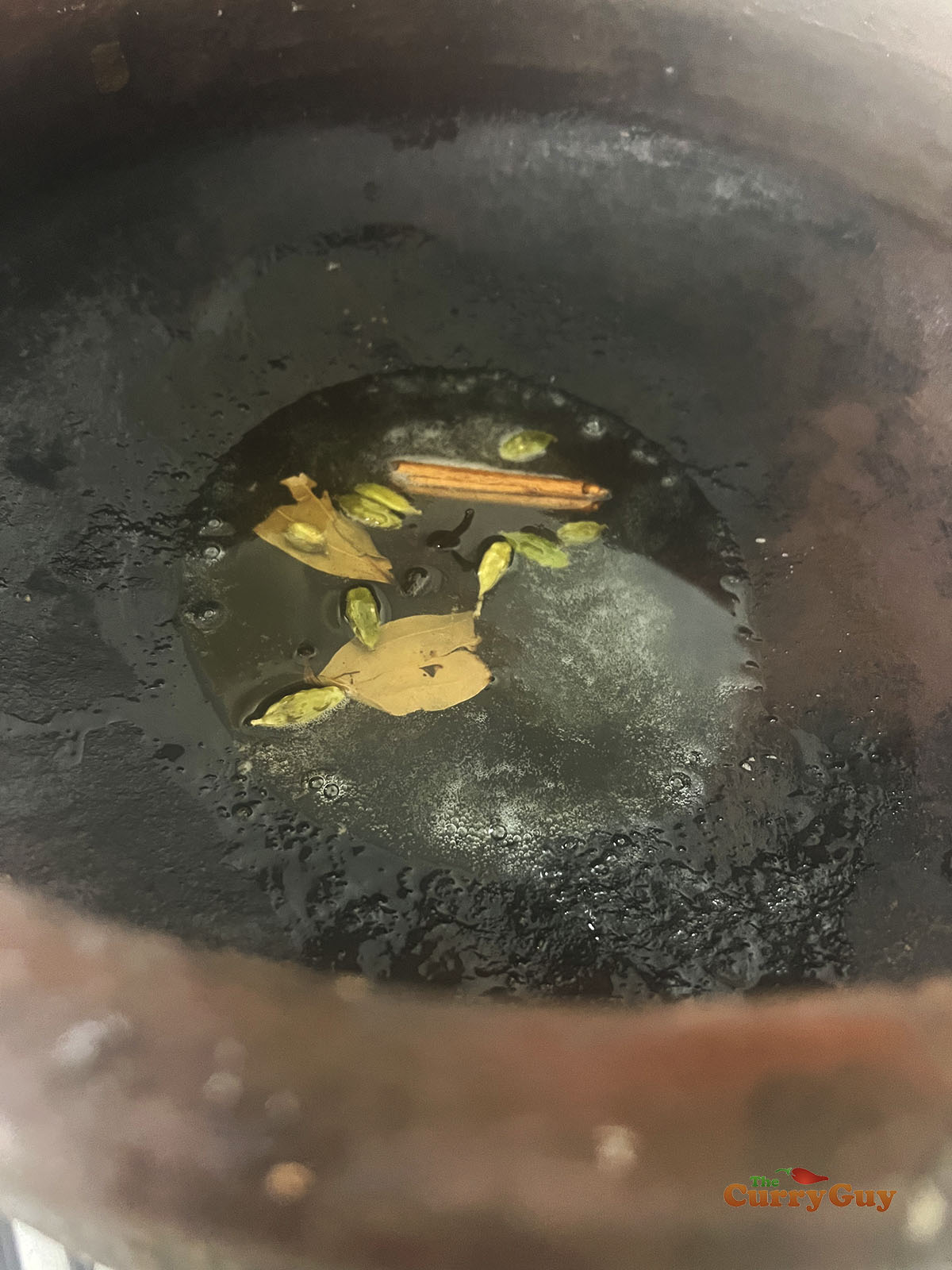 Infusing spices in ghee in a pot.