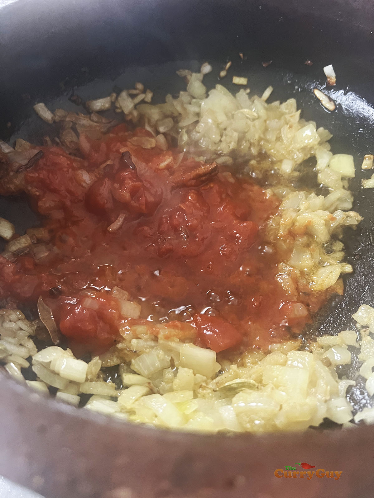 Adding ground spices and tomatoes to the curry.