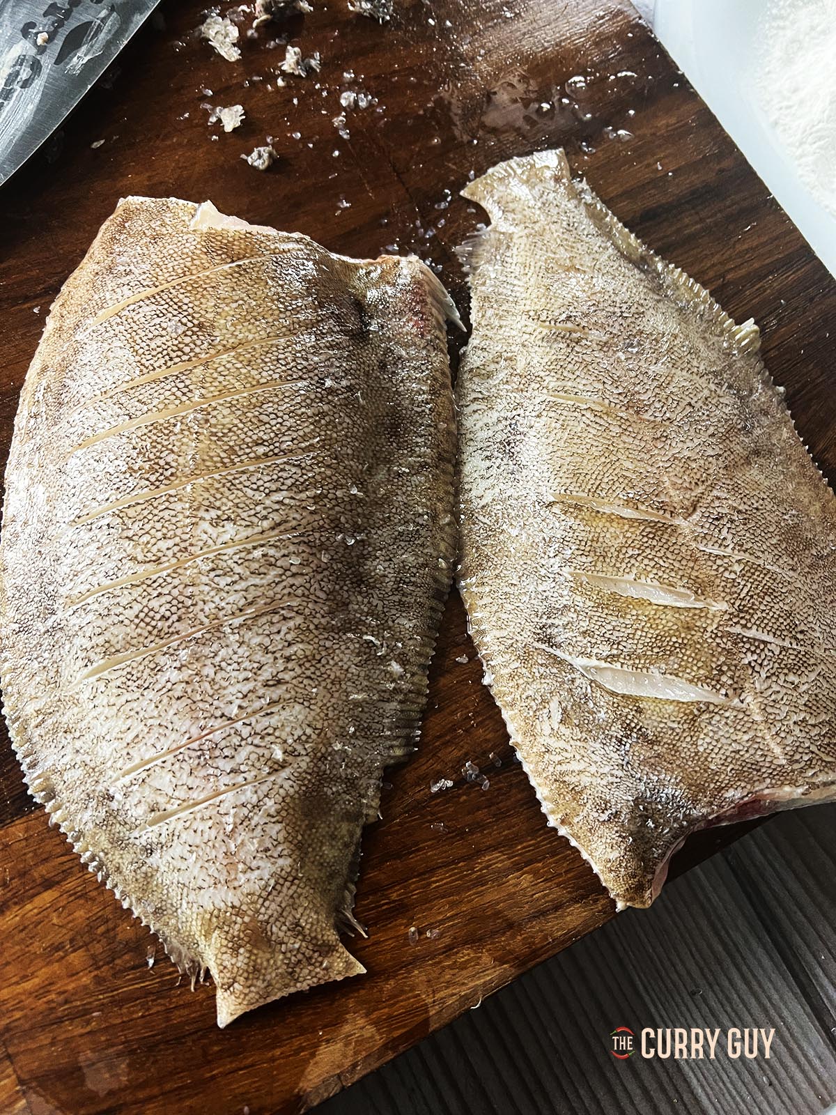 Two lemon sole with heads chopped off and the tail and fins trimmed.