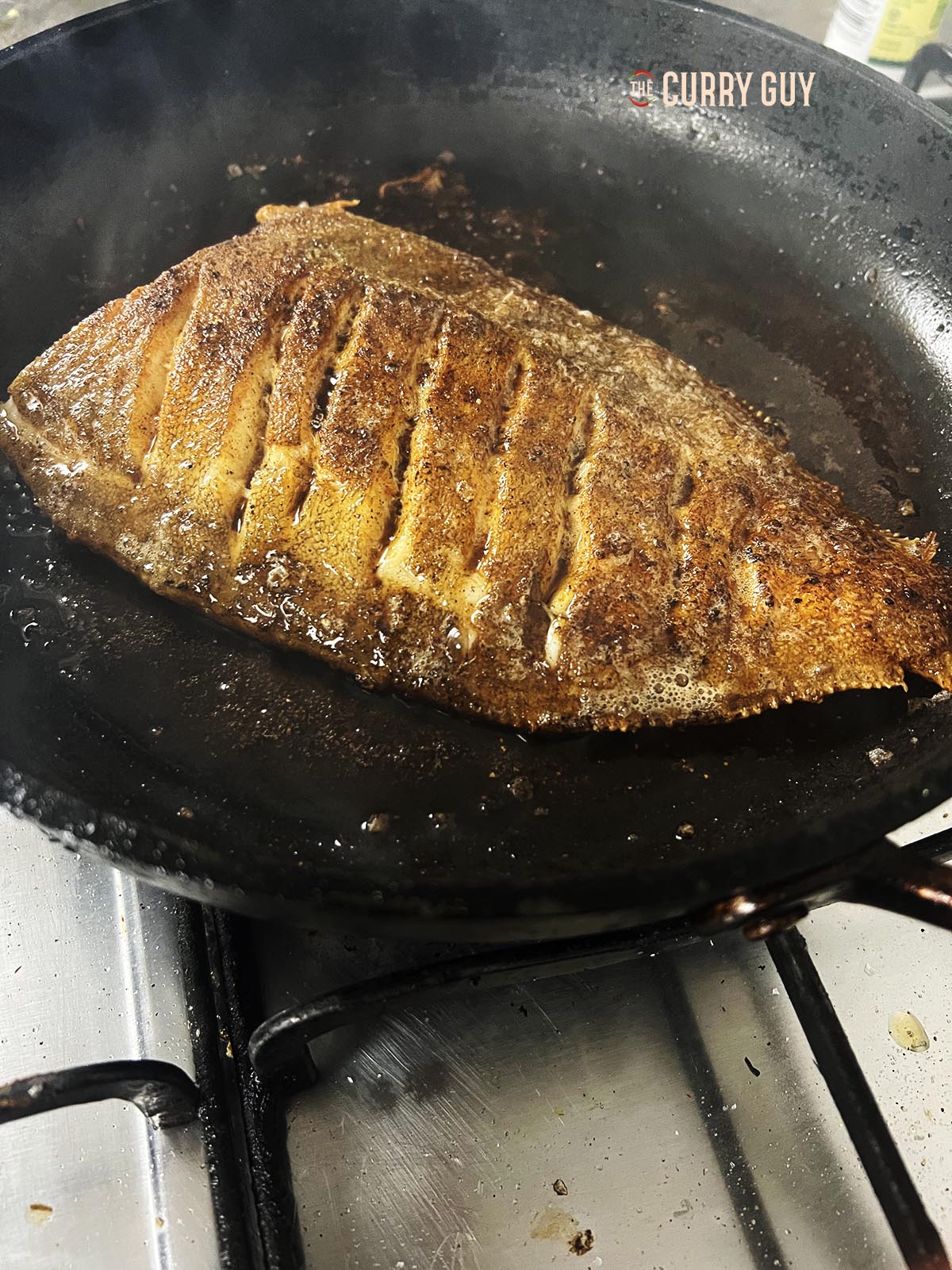 Flipping the fish over to cook the other side.