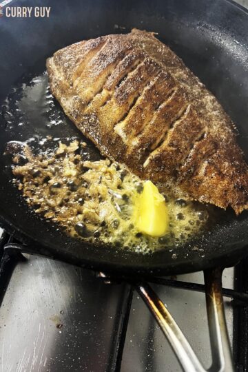 Lemon sole fried until crispy in a pan with garlic and butter.