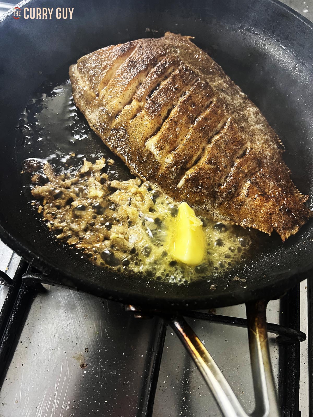 Lemon sole fried until crispy in a pan with garlic and butter.