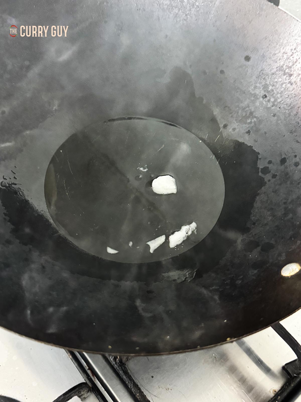Heating the coconut oil over a high heat in a wok.