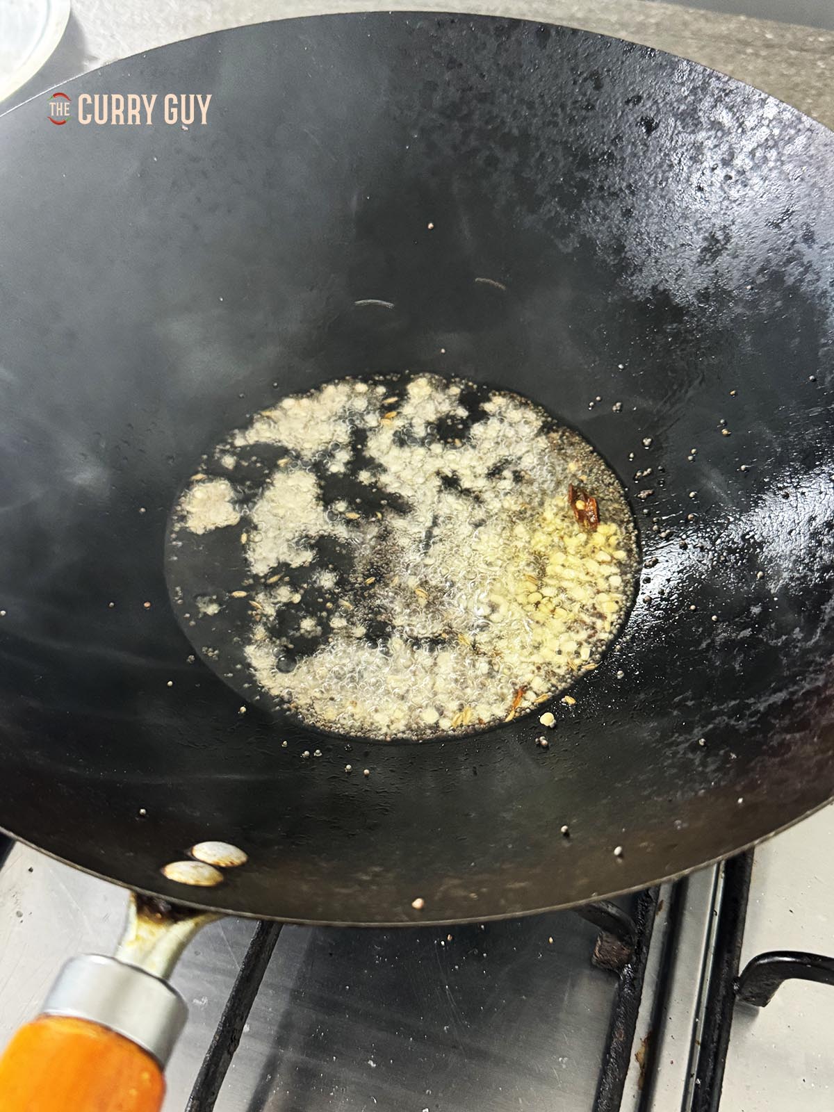 Adding the mustard seeds, urad dal and cumin to the pan.