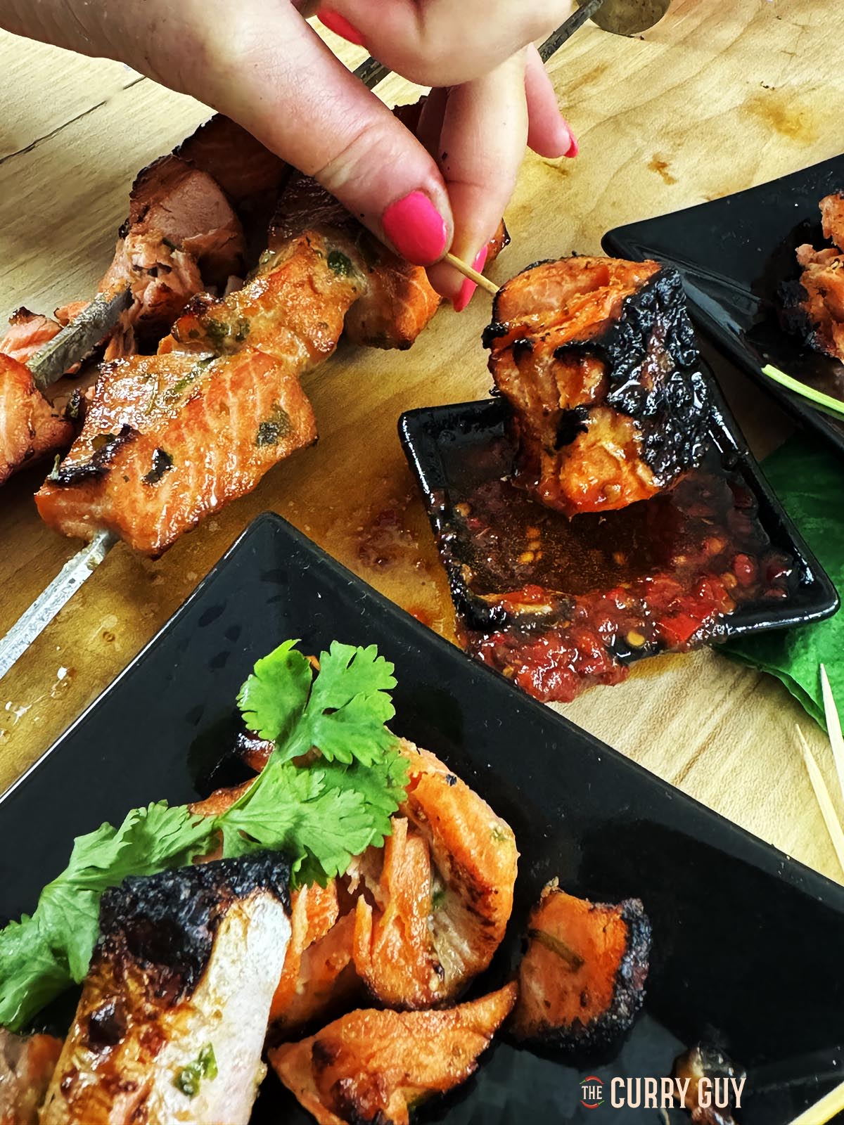 Dipping a piece of the salmon tikka in soy sauce.