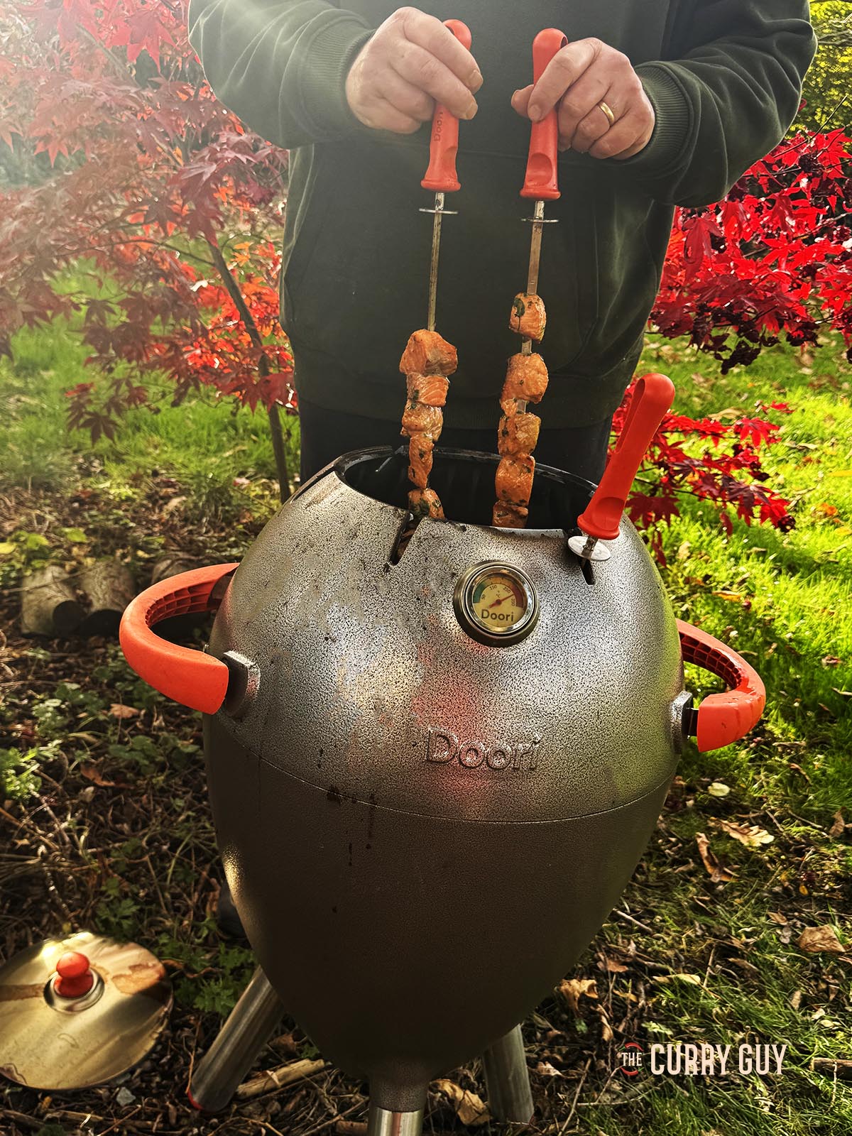 Placing the salmon skewers in a hot tandoor oven.