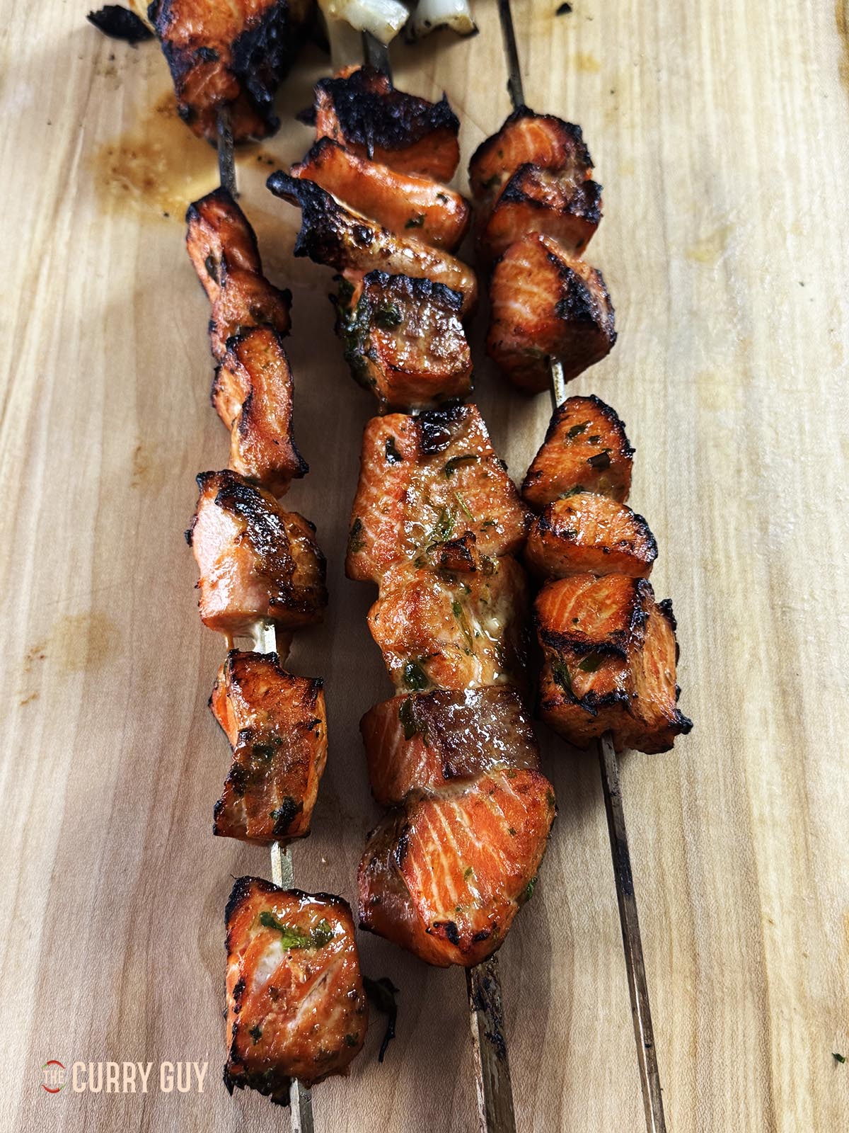 The skewered and cooked salmon tikka on a work surface.