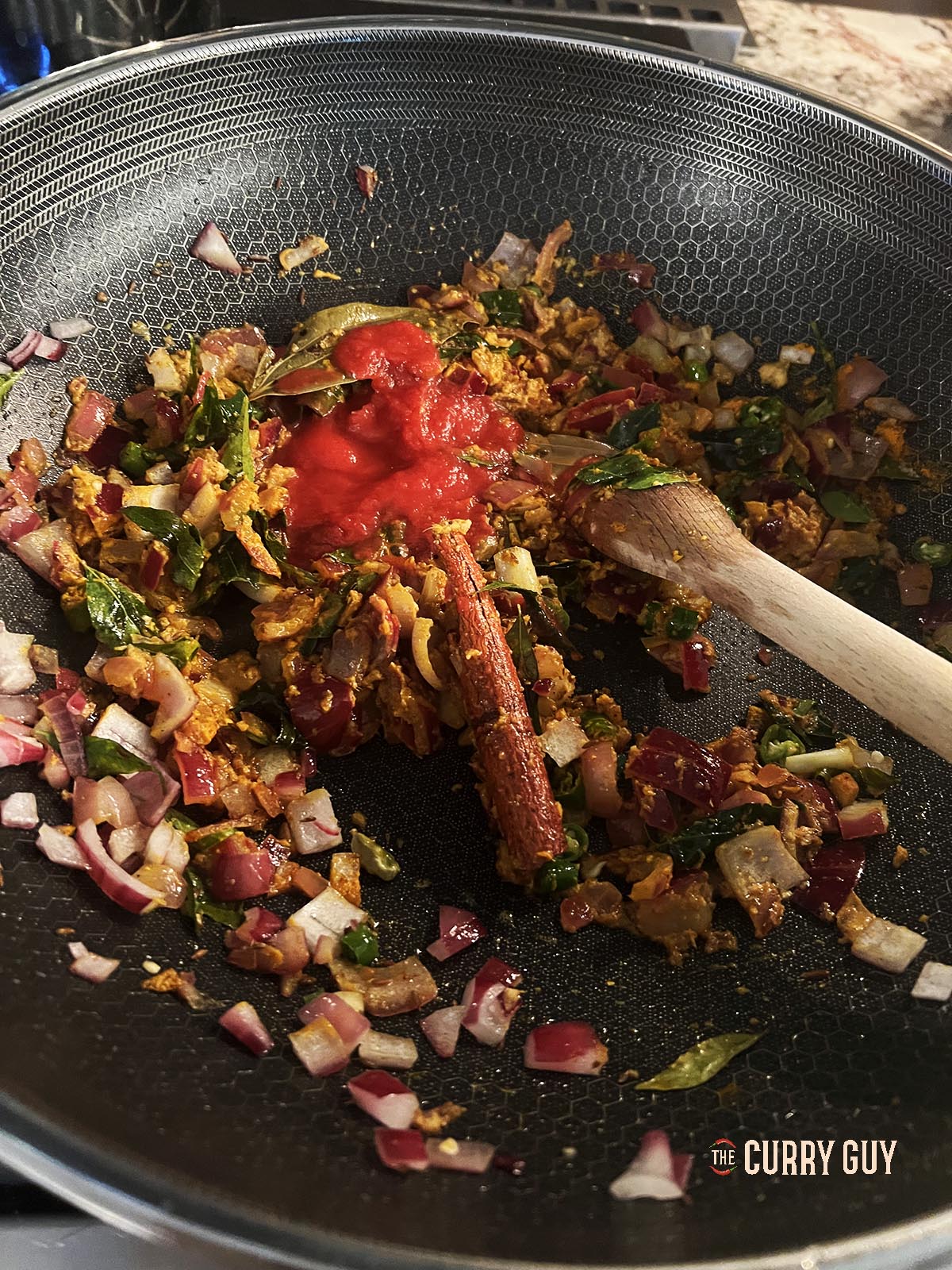 Adding ground spices to the curry.