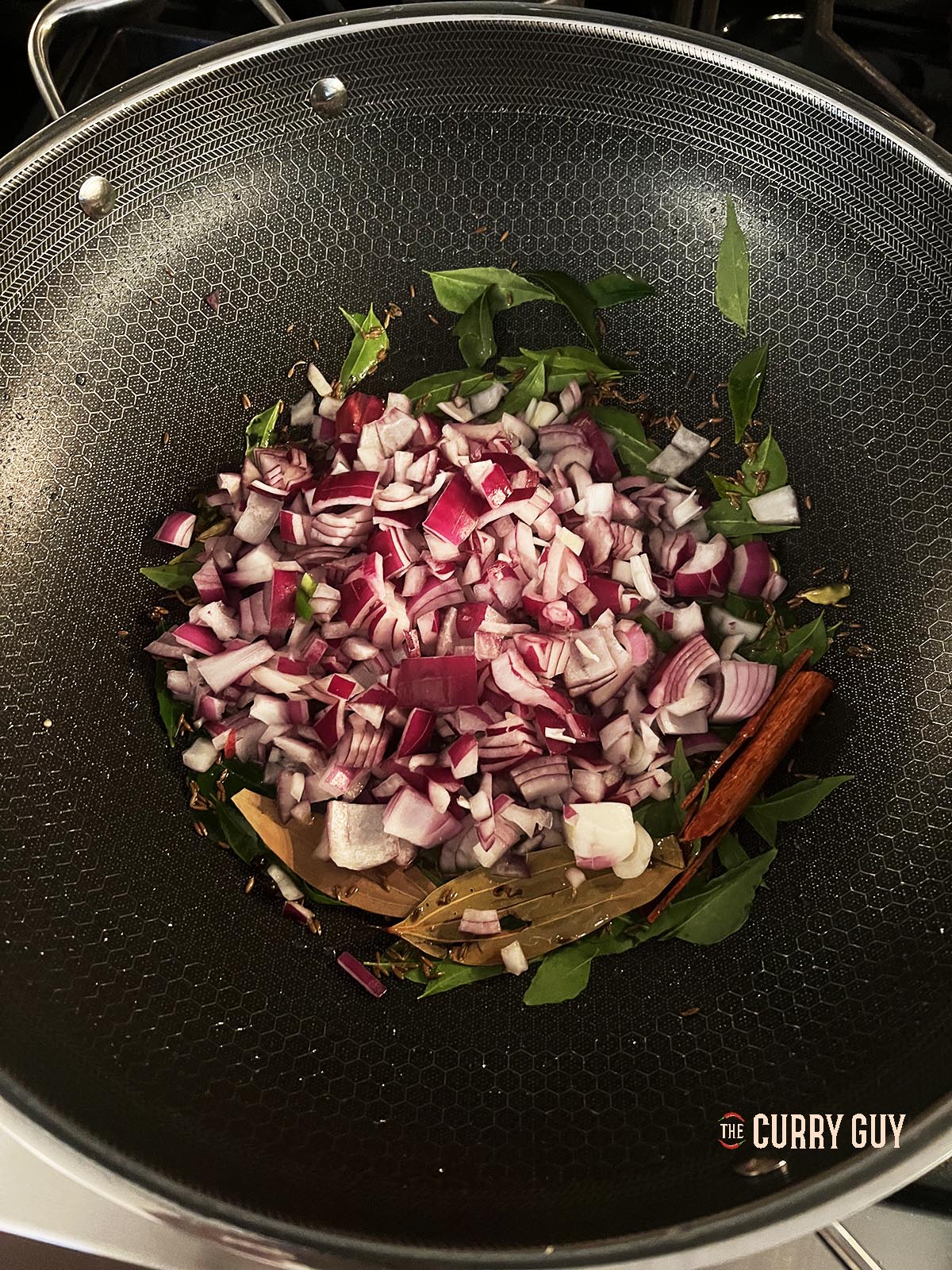 Stirring in the chopped onions to brown in the hot ghee.