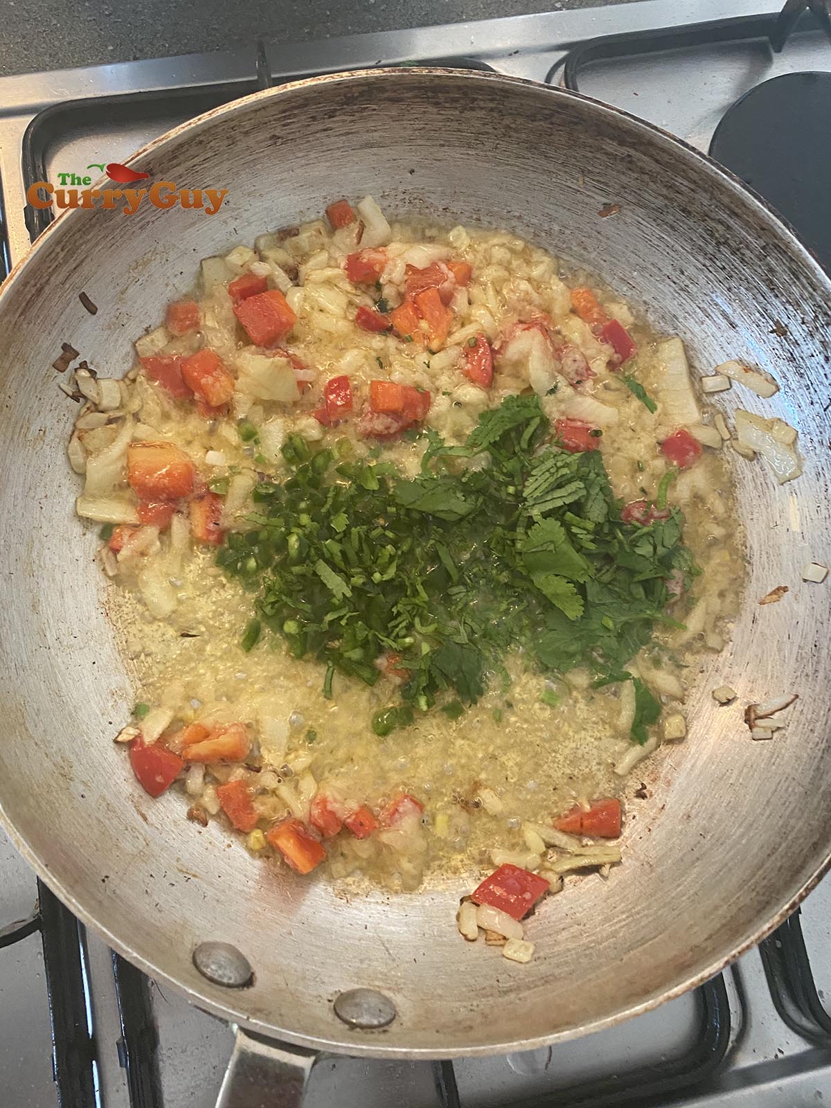 adding coriander stalks and chillies to pan