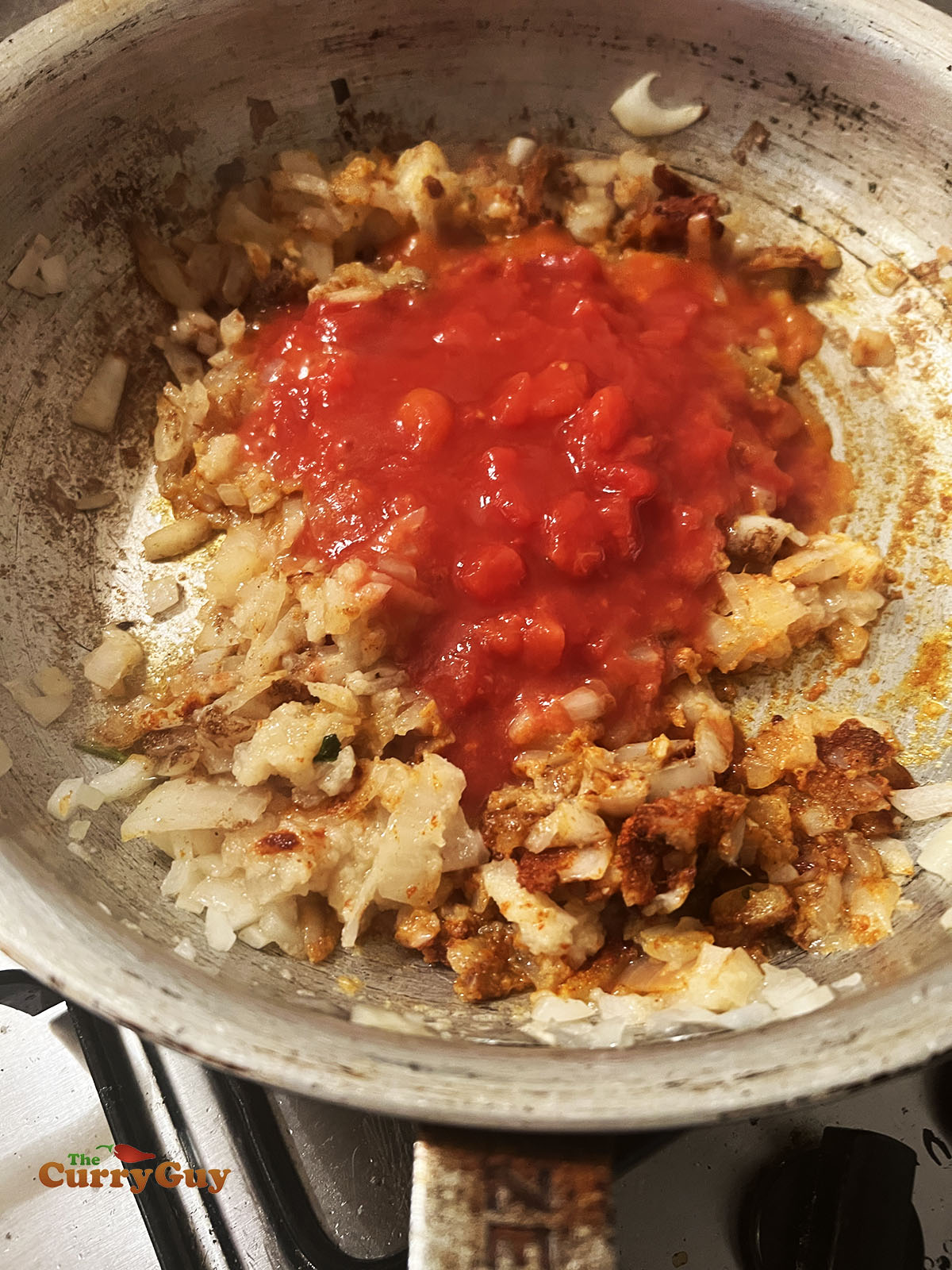 Adding chopped tomatoes to the pan