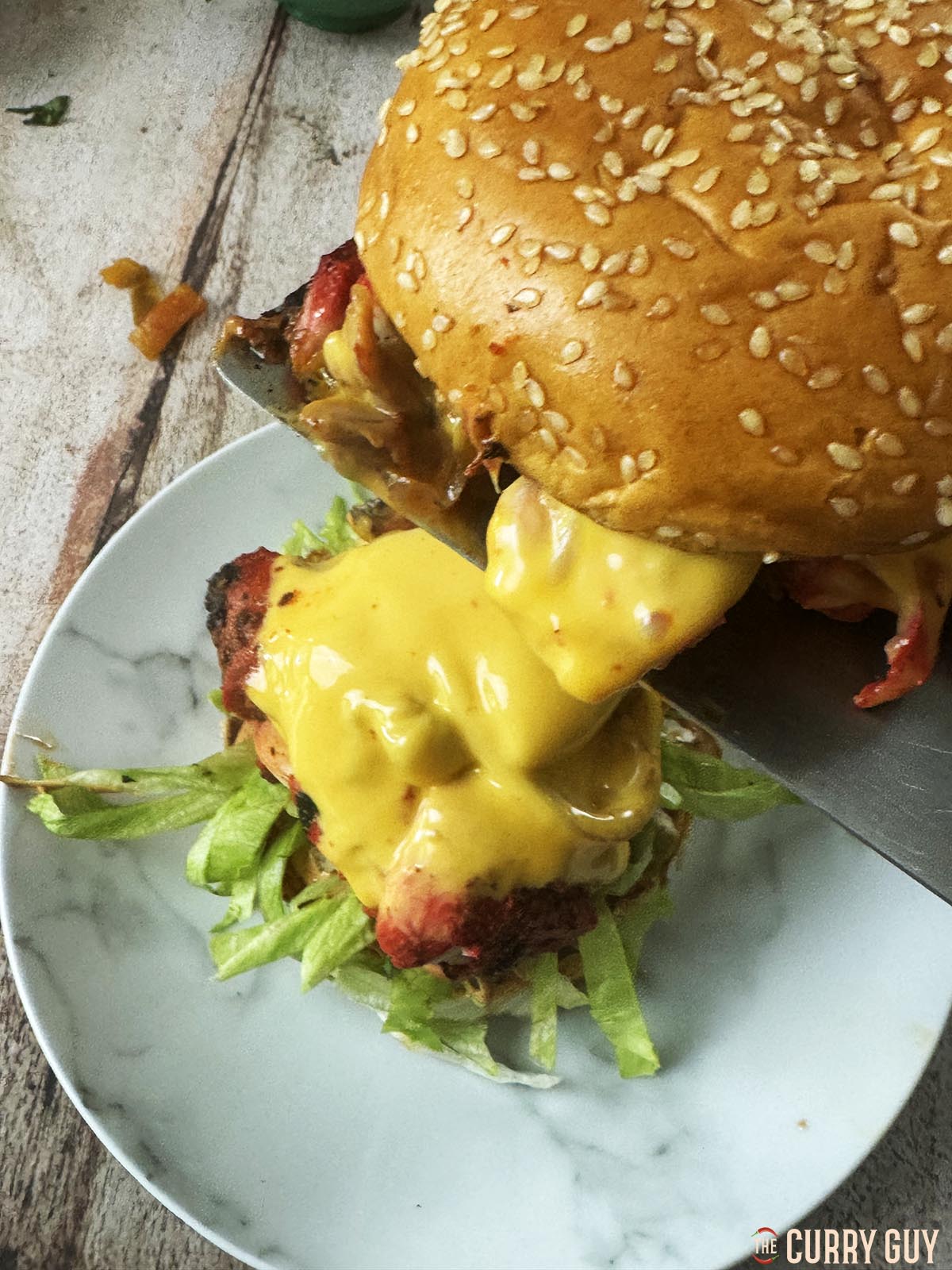 Topping the burger with the other mound of cheese and chicken with the top bun.