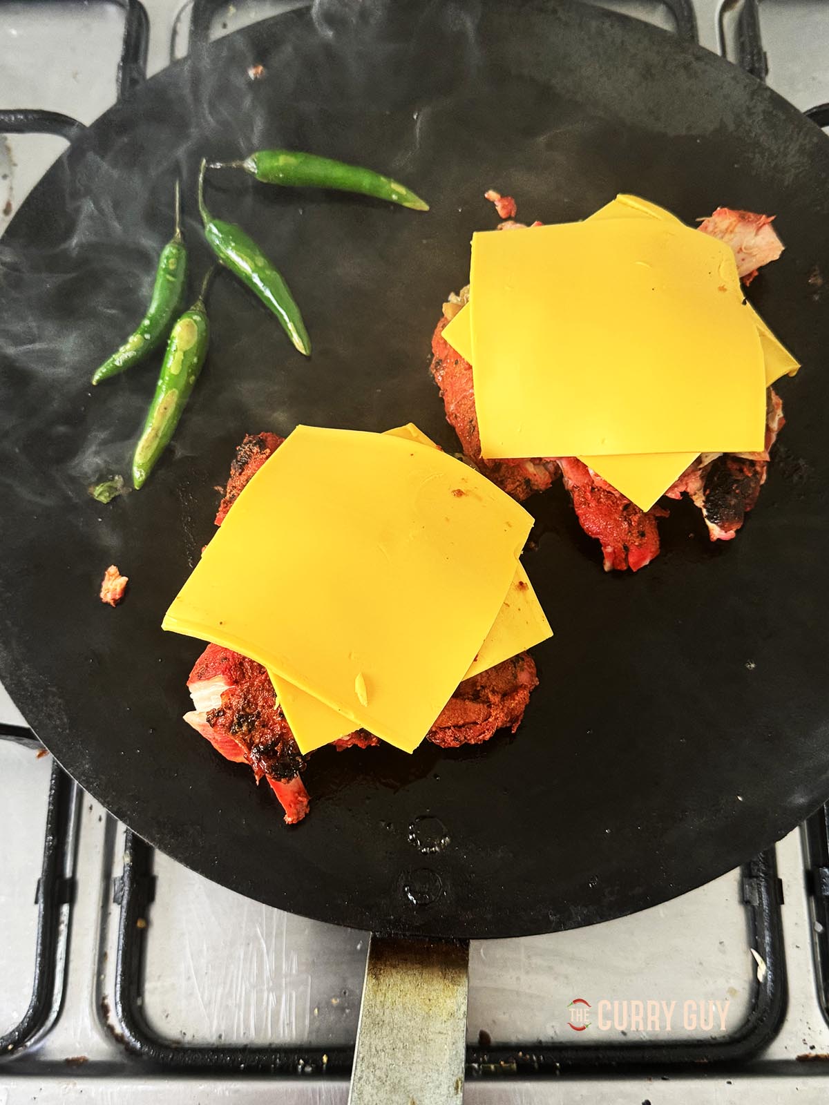 Topping the tandoori chicken mounds with American cheese slices.