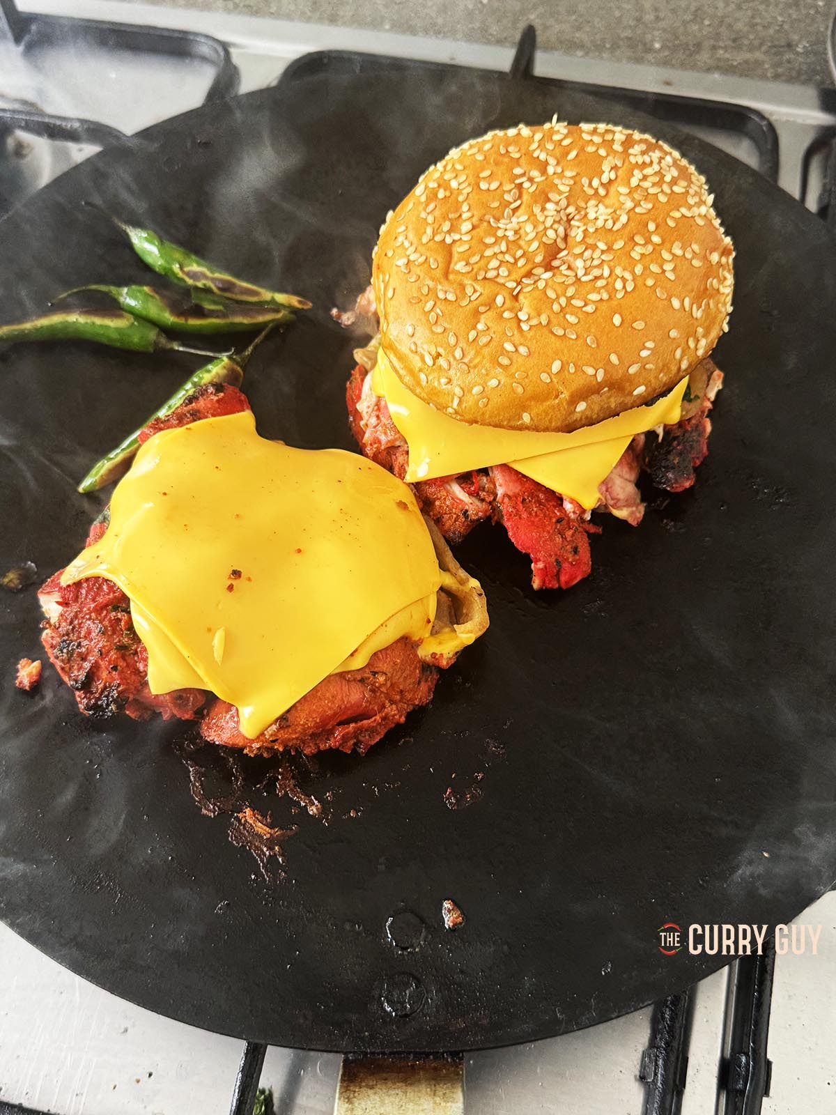 Adding the top bun to one of the chicken and cheese mounds.