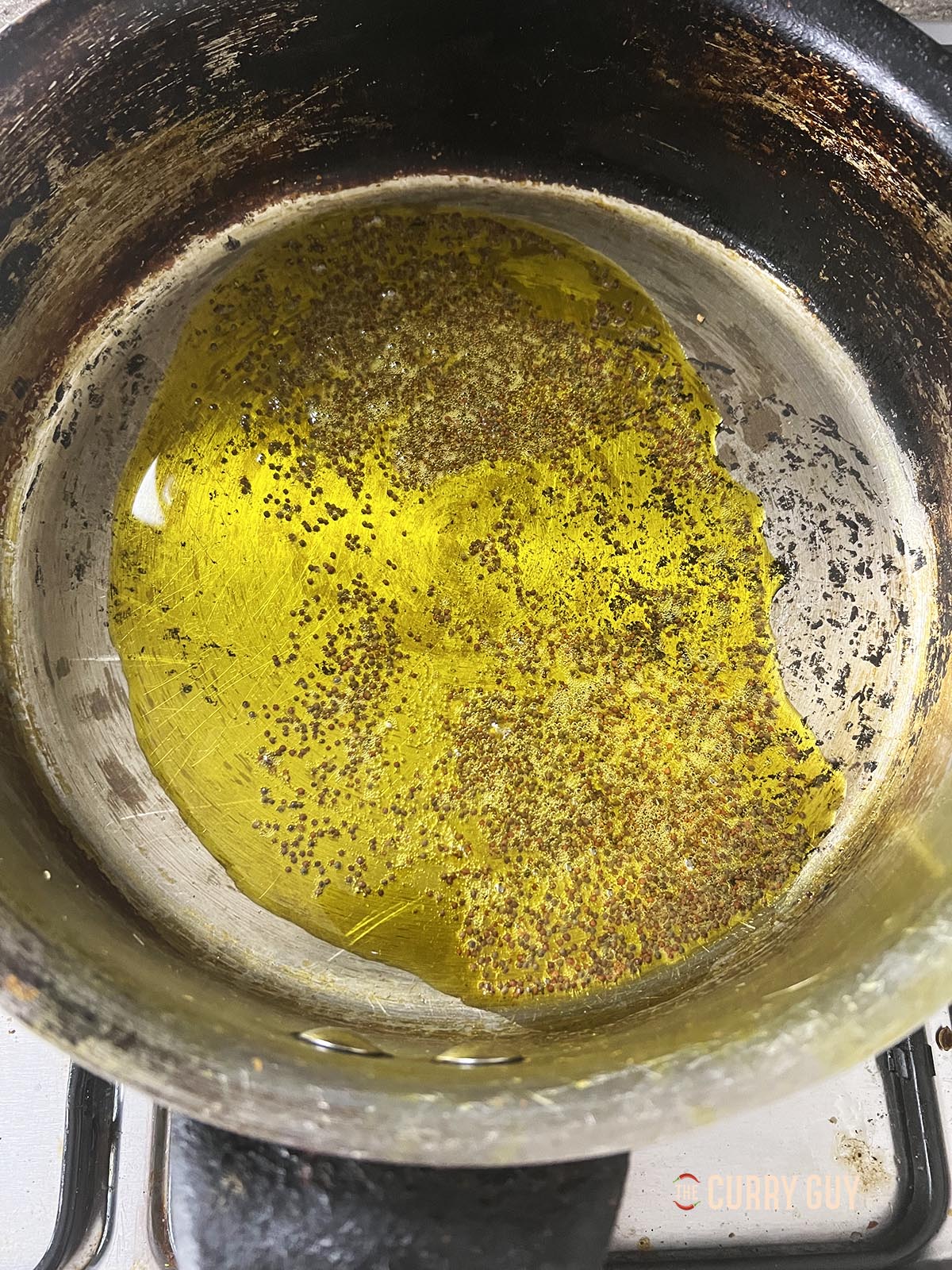 Adding oil and mustard seeds to the pan over a medium high heat.