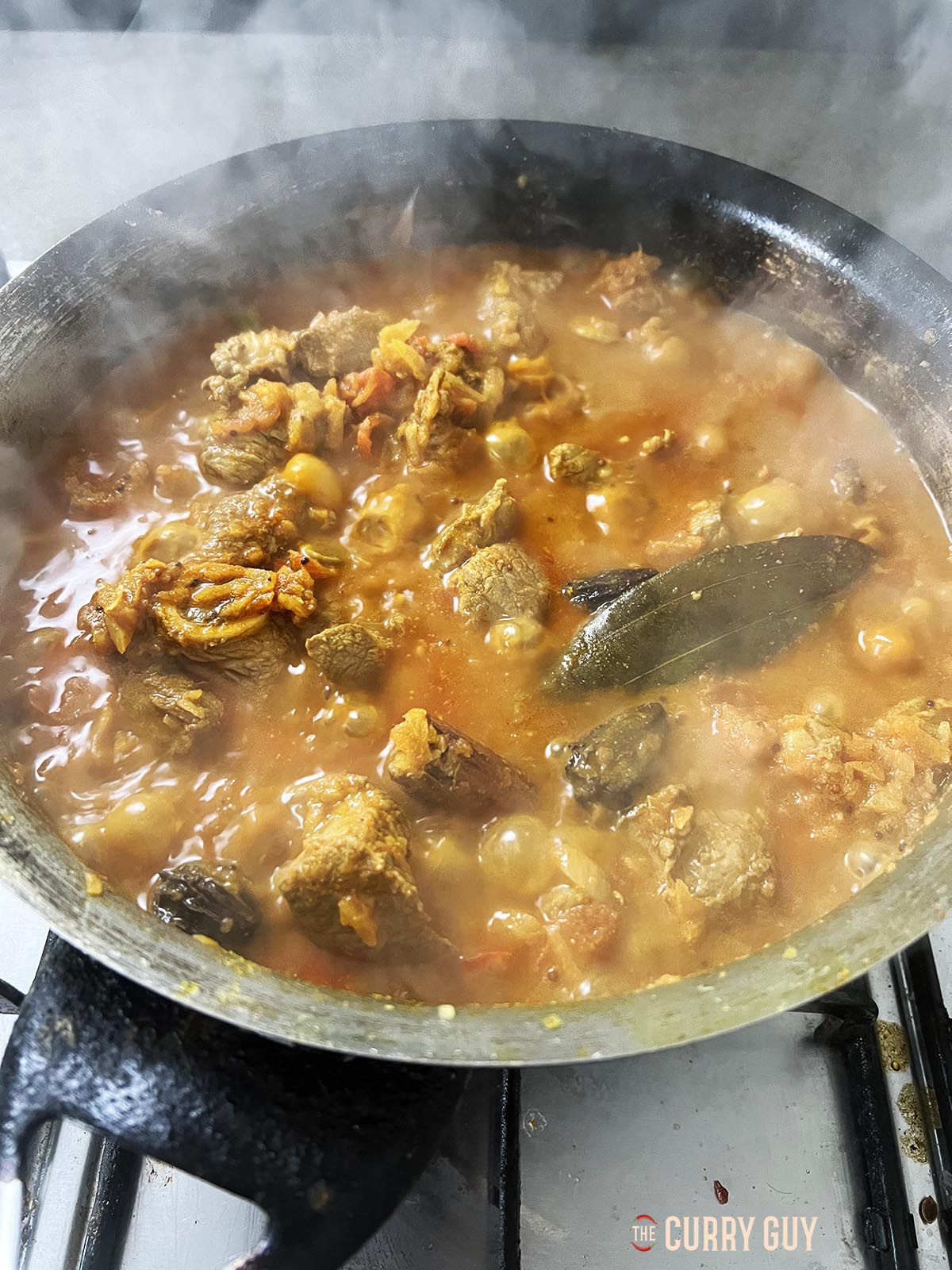 The pan with more liquid in it due to the meat and tomatoes releasing moisture.