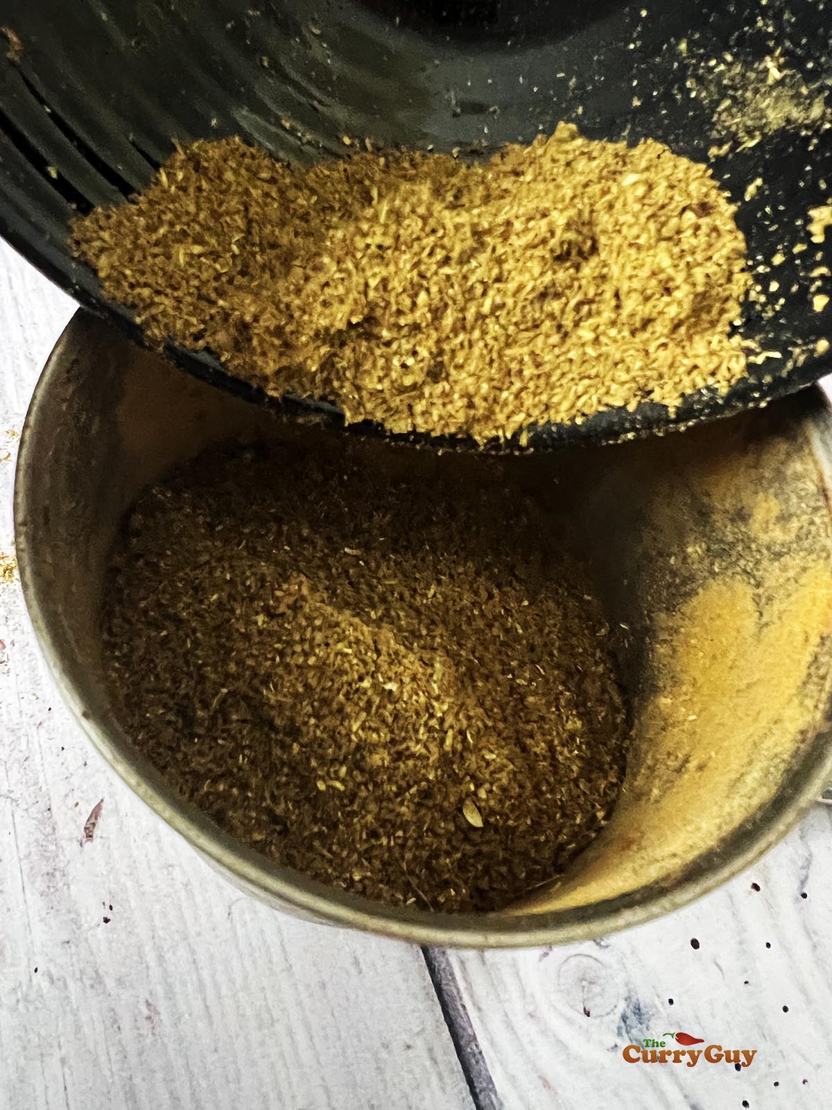 Pouring the garam masala into an air-tight container.
