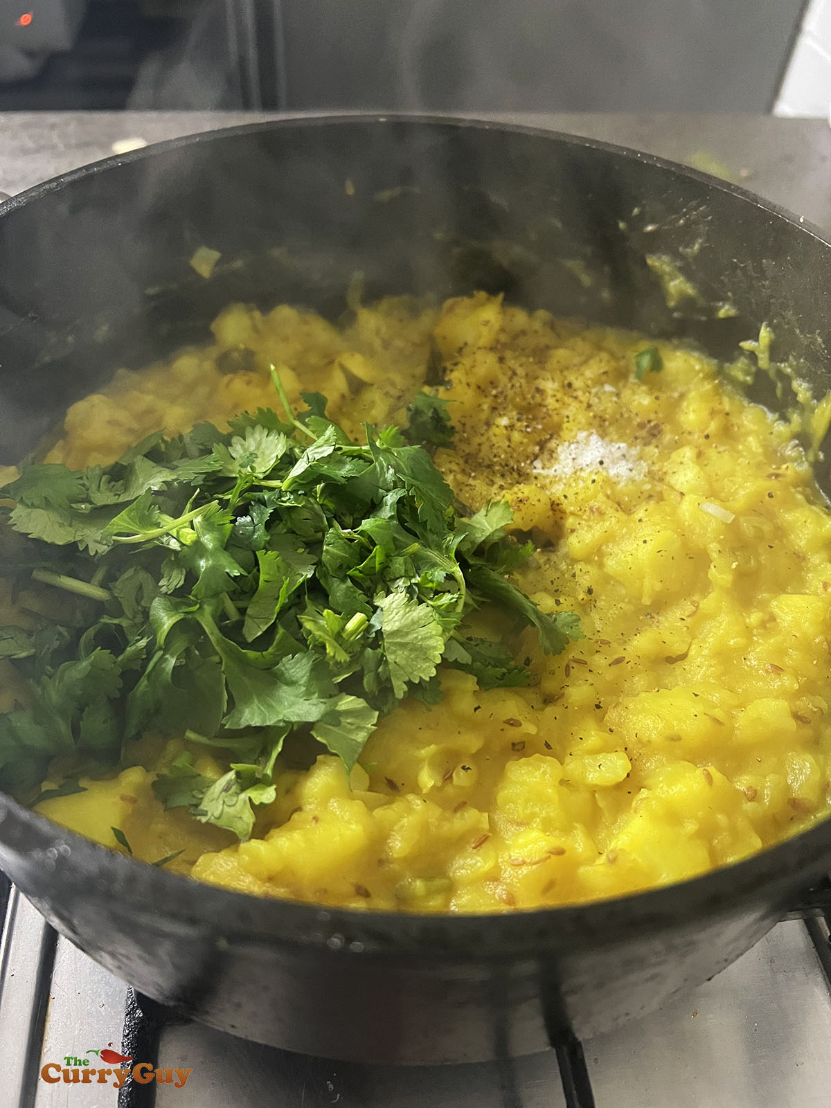 Adding coriander and salt to the potato mixture.