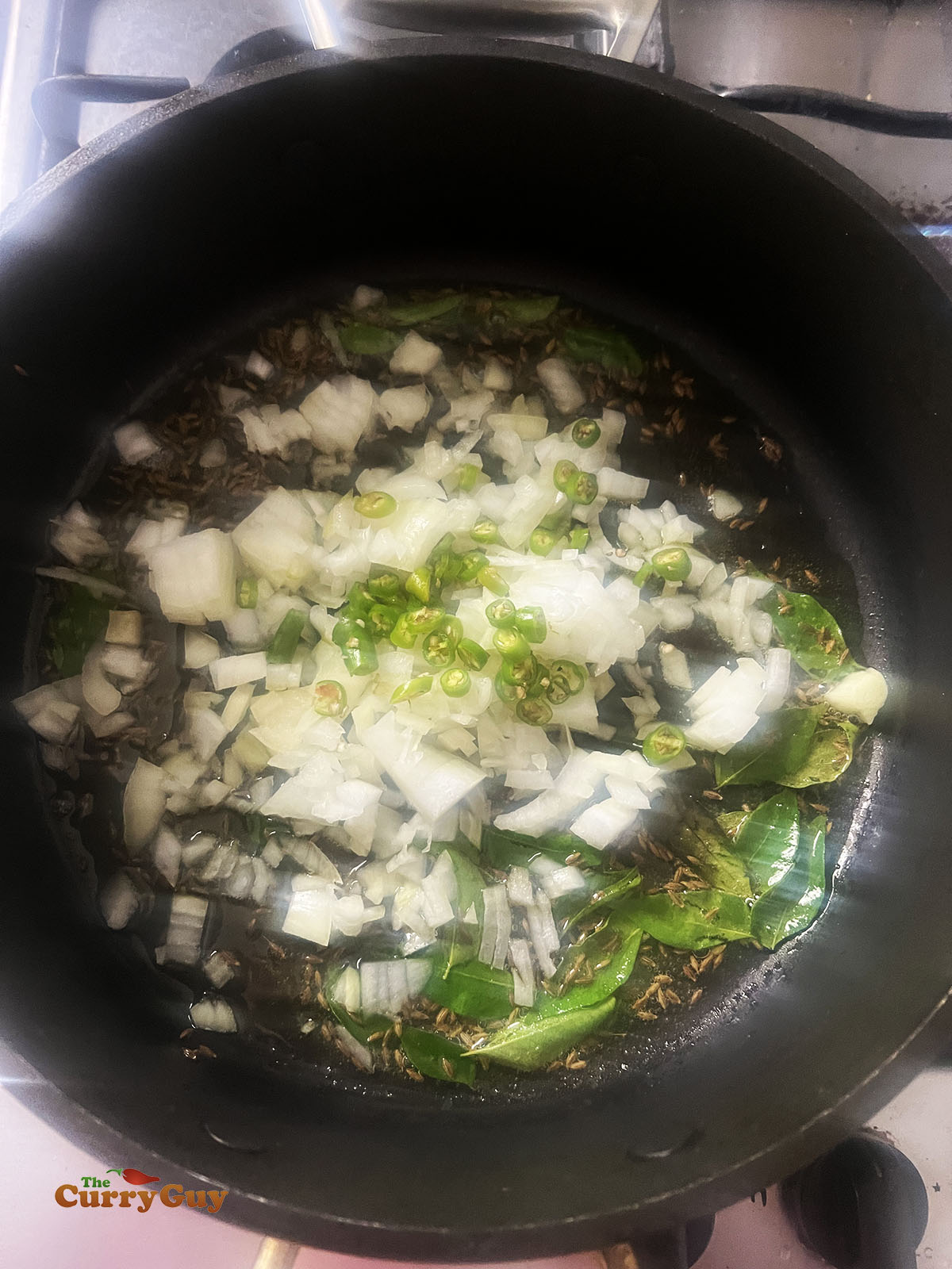 Frying chillies, onion and curry leaves