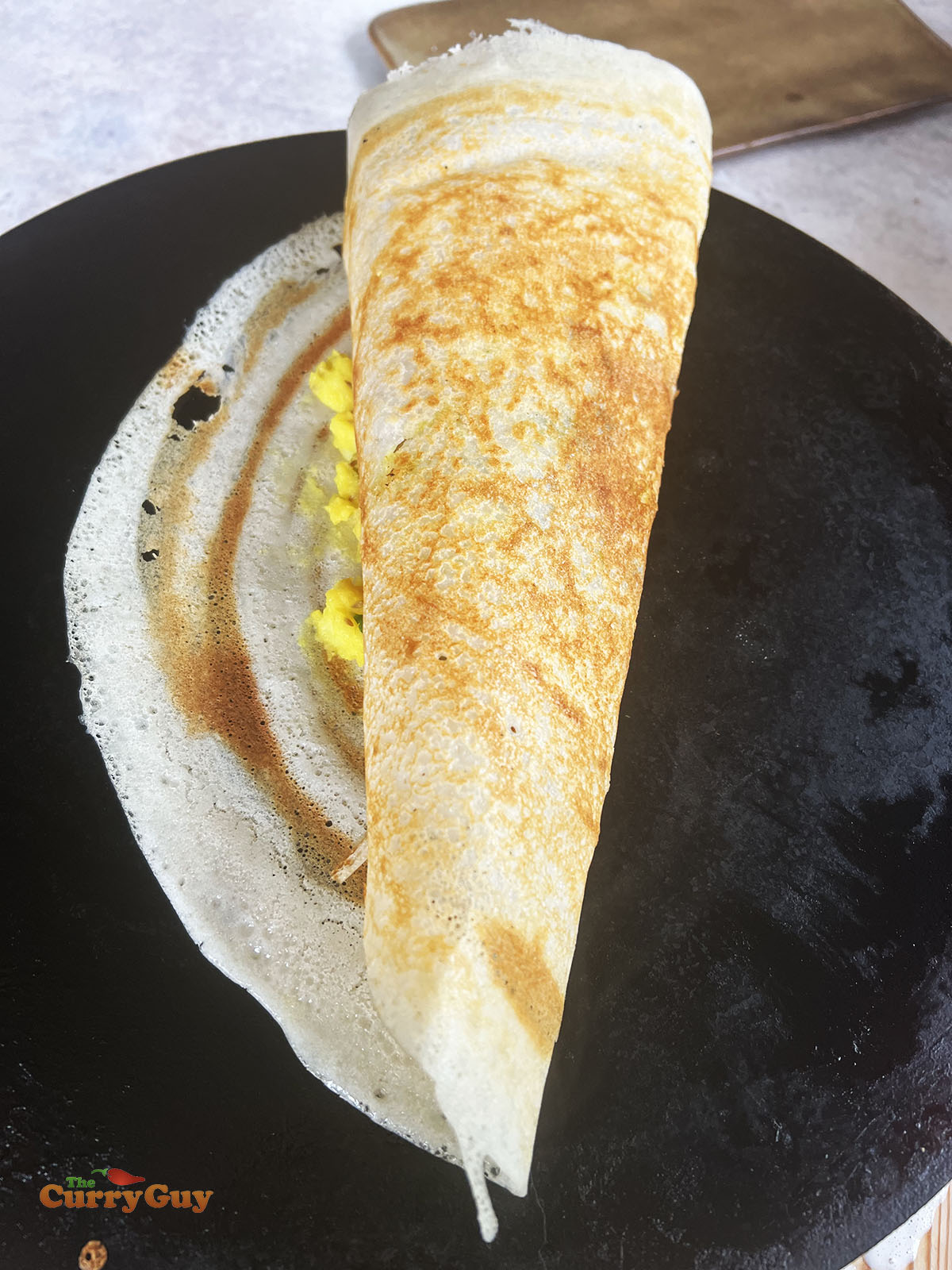 Checking for doneness and folding the dosa over