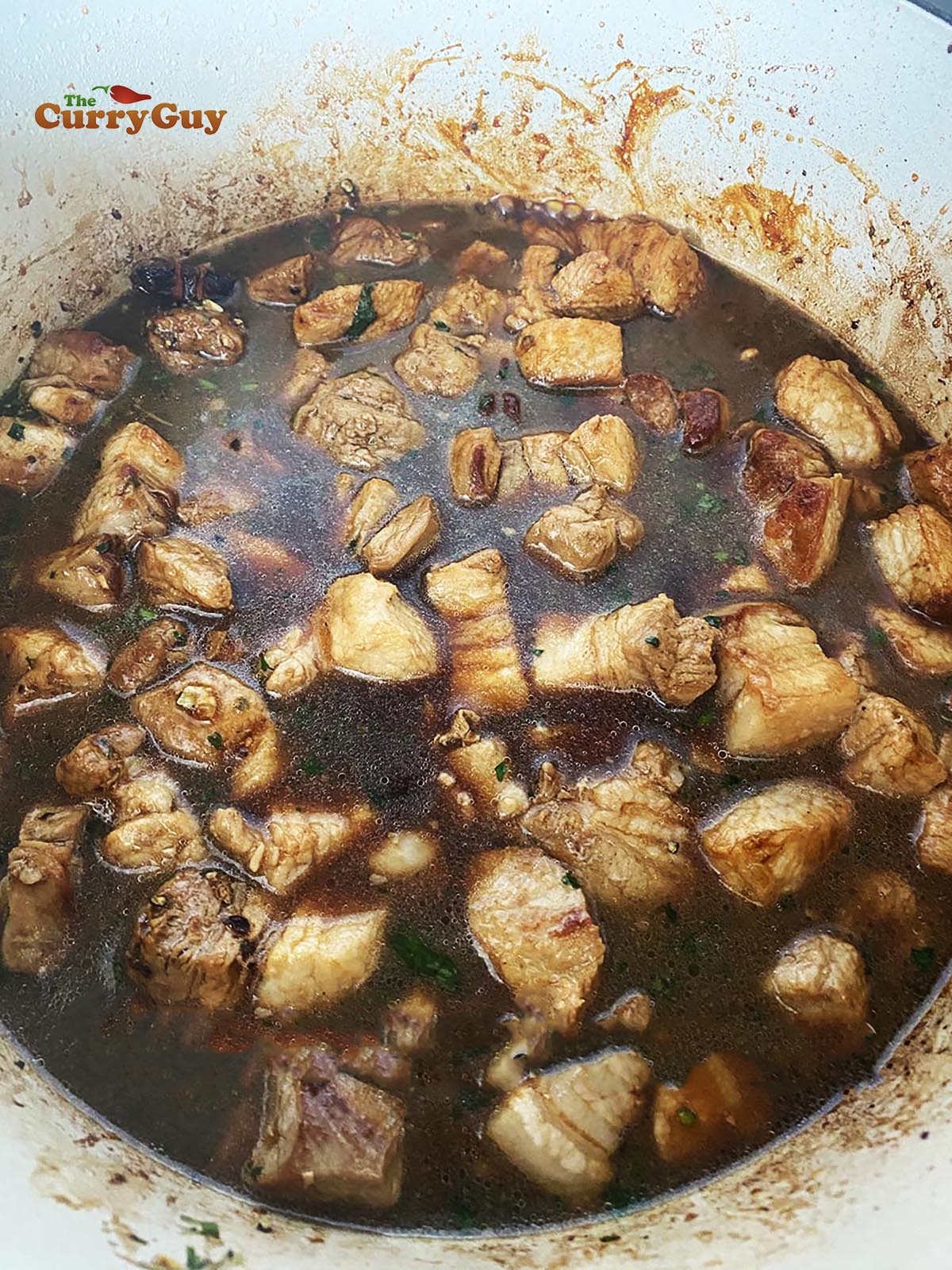 Simmering the pork belly in the sauce. 