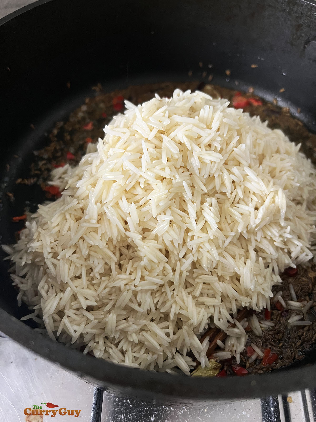 Adding rice to the ghee and spices.